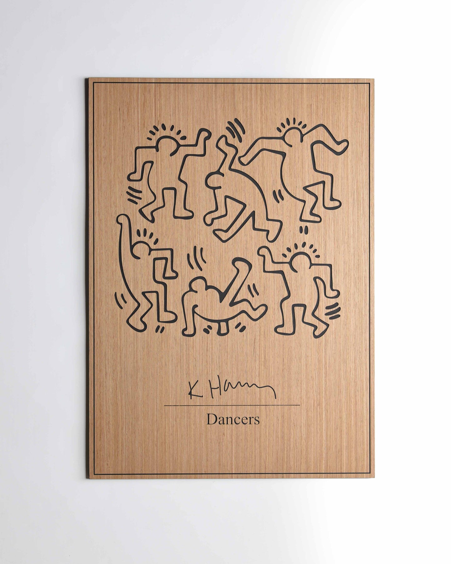 Tight shot capturing carved silhouettes of dancers in a fluid arrangement, blending bold black fills and textured woodgrain details.