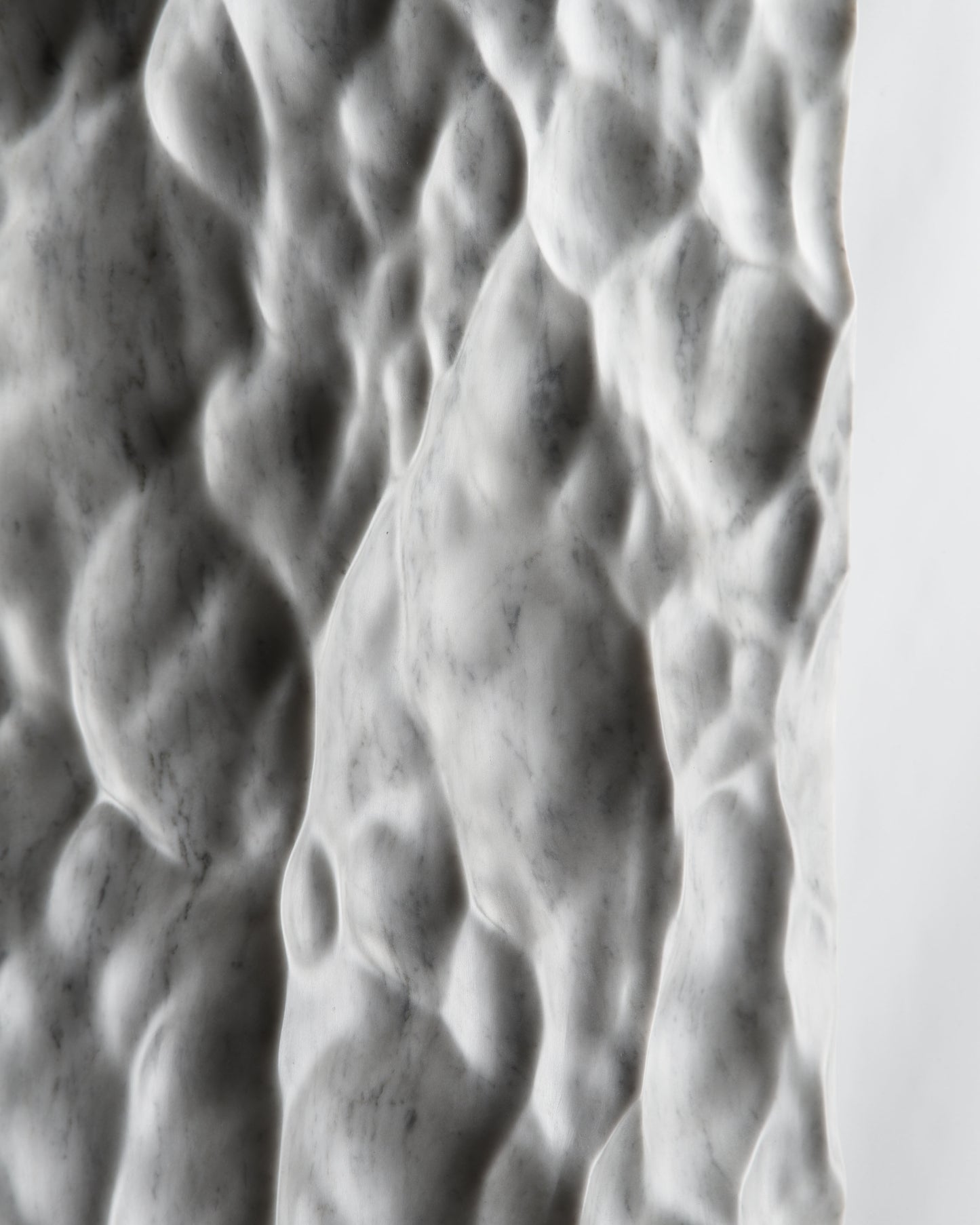 Close up of deep carved relief on Carrara marble with dramatic shadow contrast