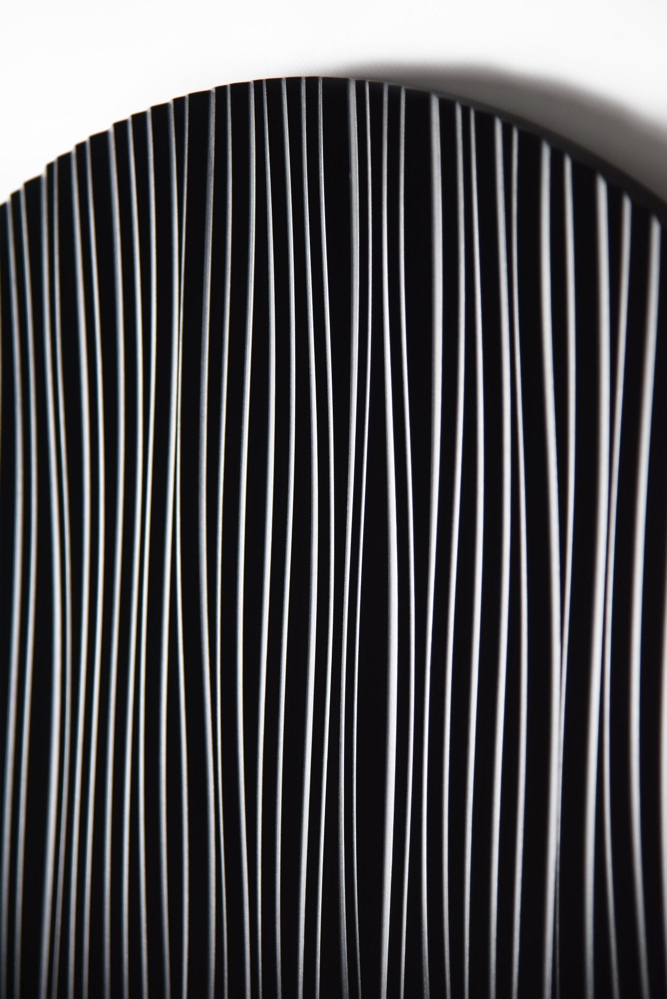 Macro detail of the vertical relief lines on the black round wall sculpture