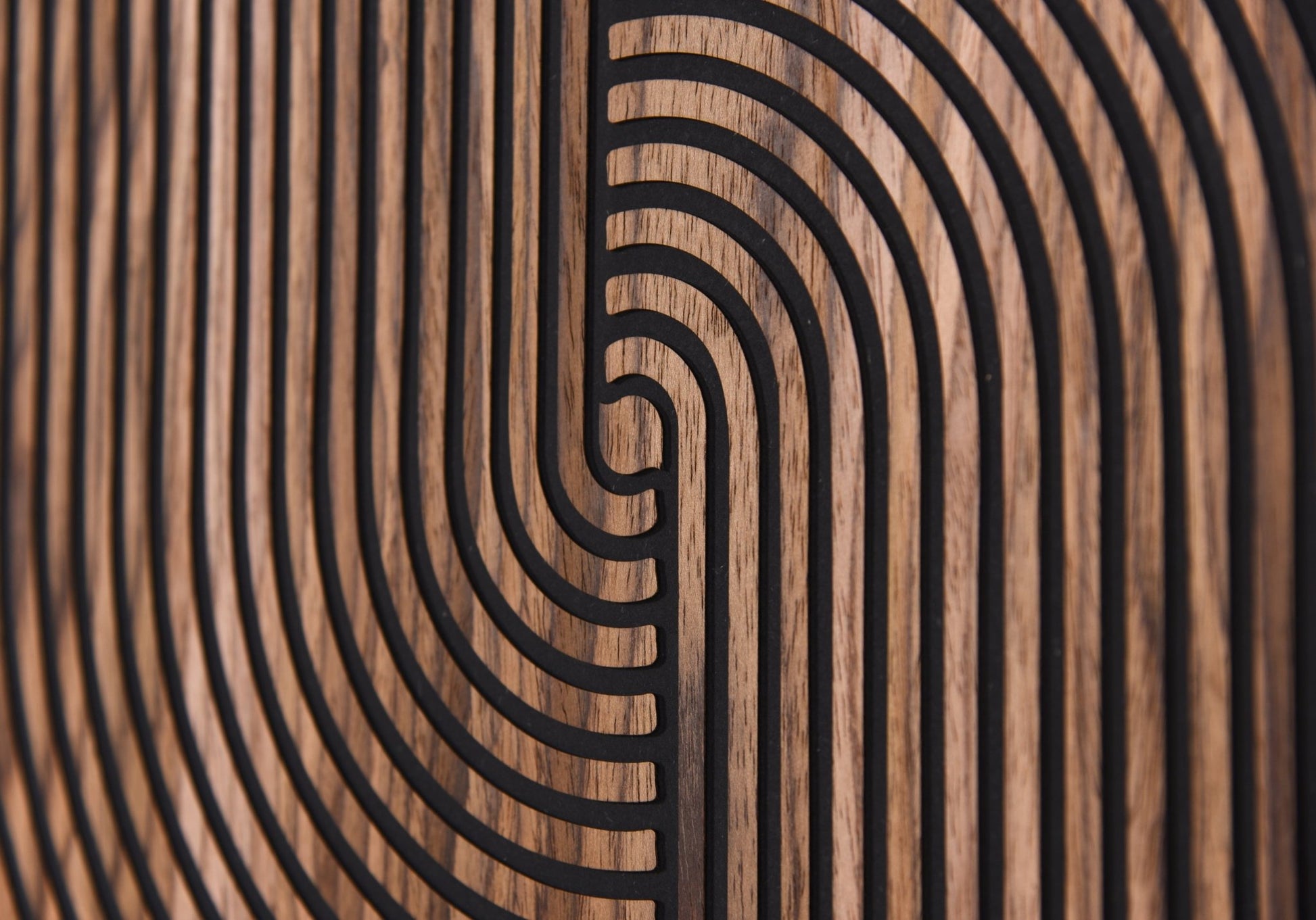 Macro detail of carved arc lines and walnut grain on black background