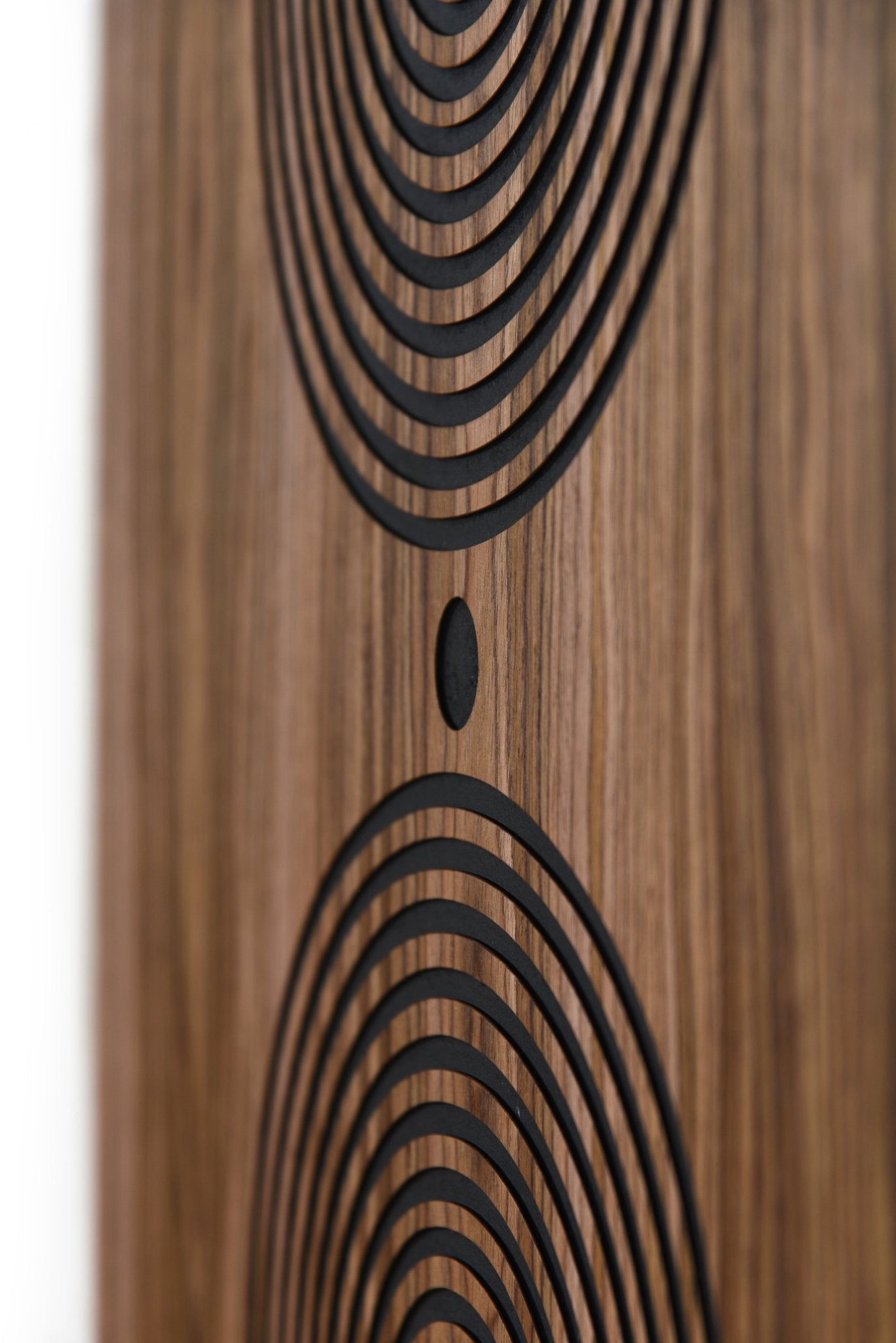 Close up of carved arcs and central dot on walnut, black groove detail