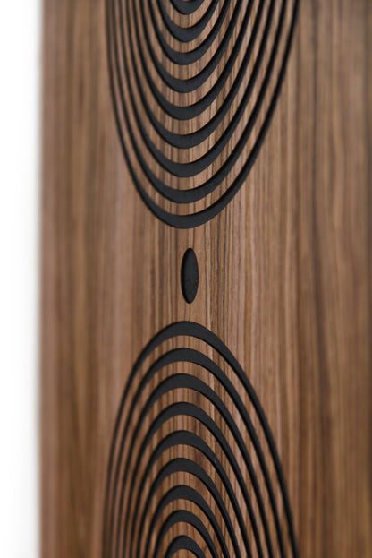 Close up of carved arcs and central dot on walnut, black groove detail