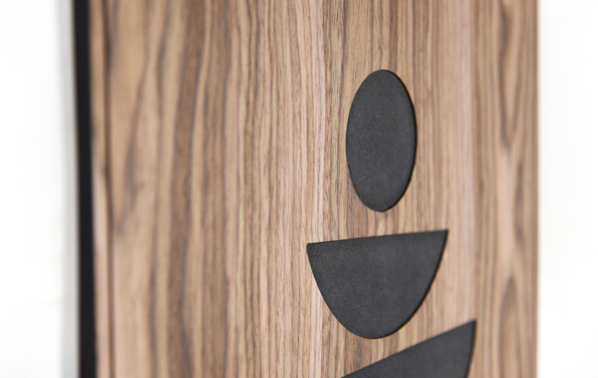 Close up of the minimal figure style shapes in black inlay on walnut