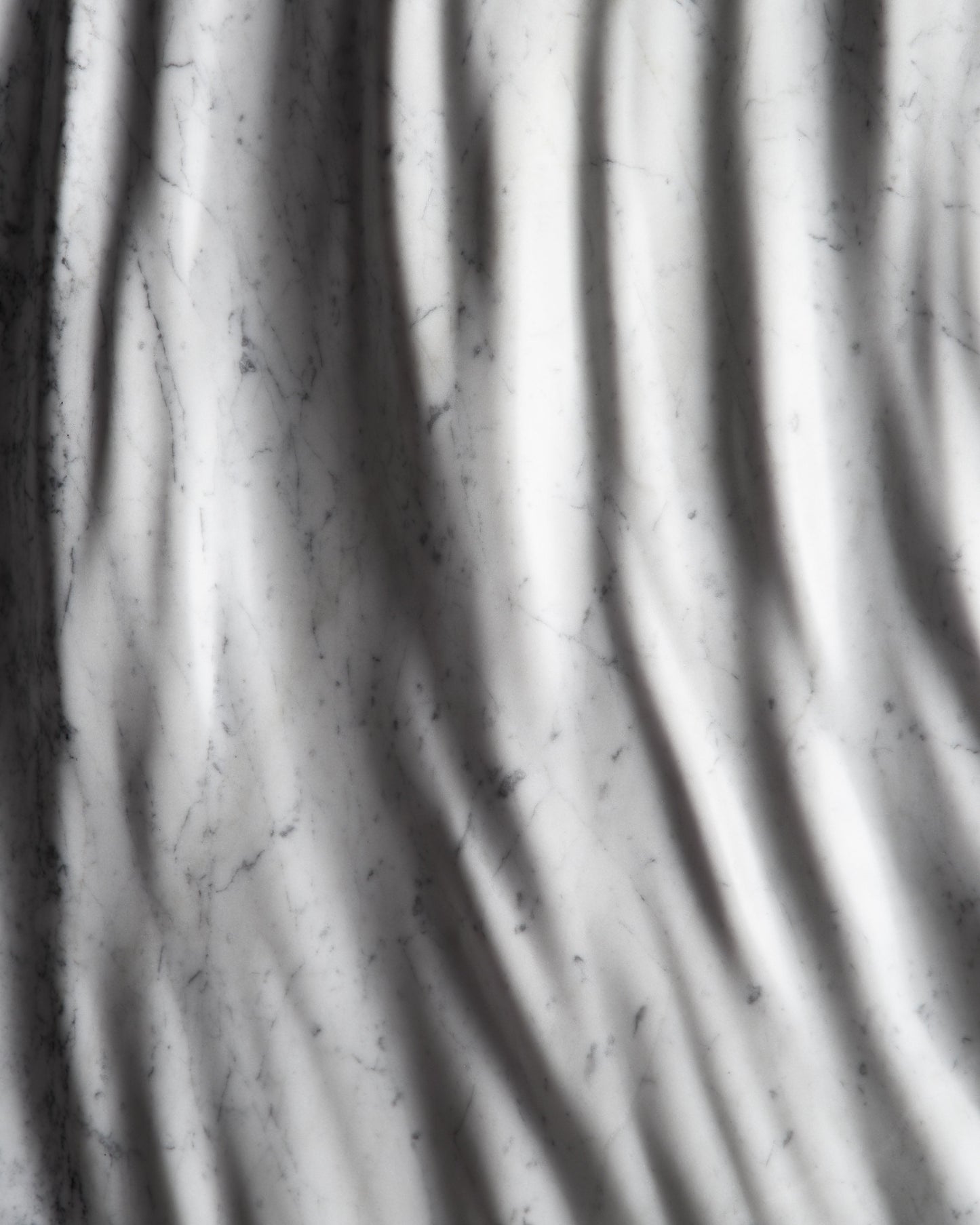 Detail of the carved marble relief with flowing folds and subtle Carrara veining