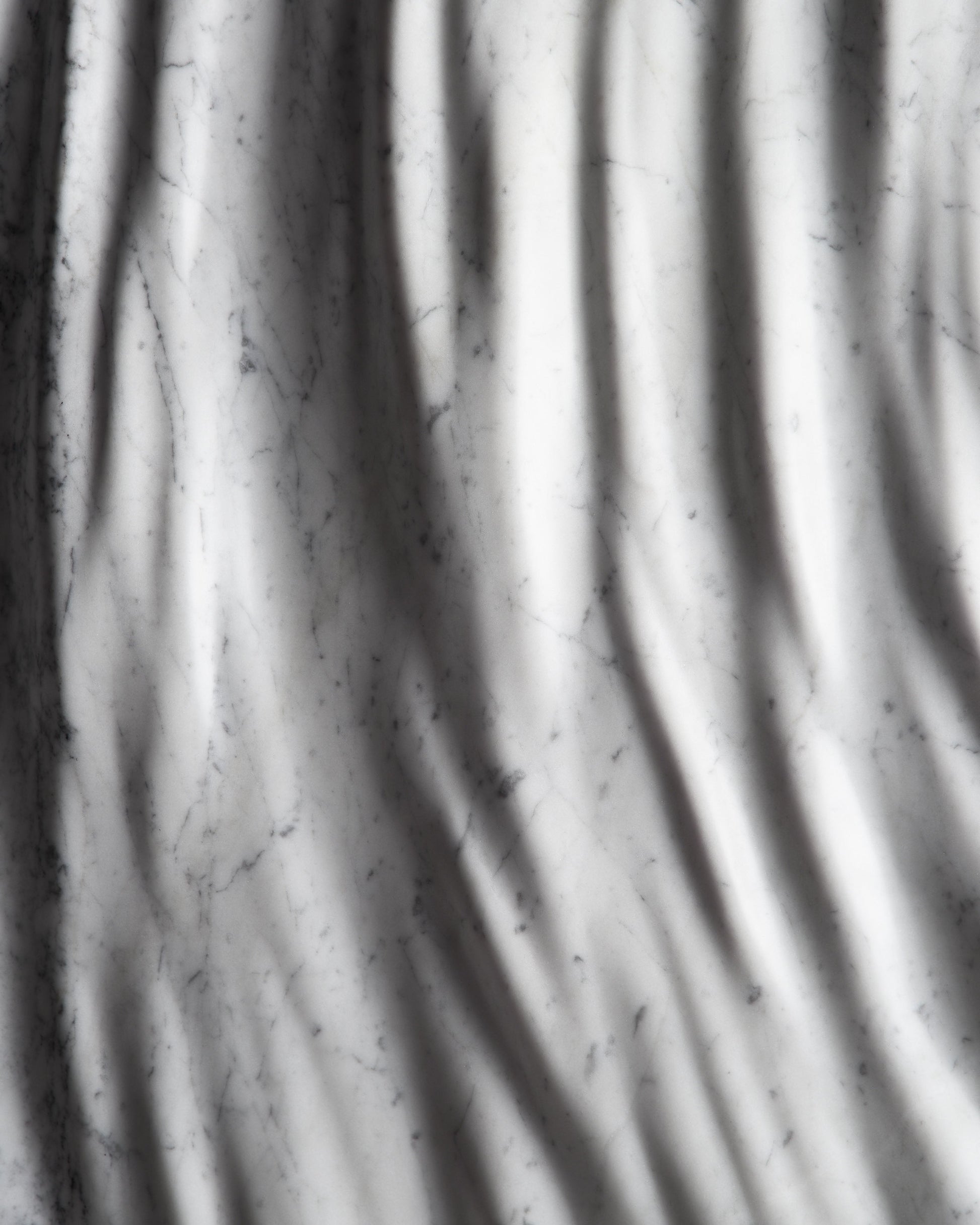 Detail of the carved marble relief with flowing folds and subtle Carrara veining