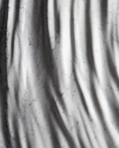 Detail of the carved marble relief with flowing folds and subtle Carrara veining
