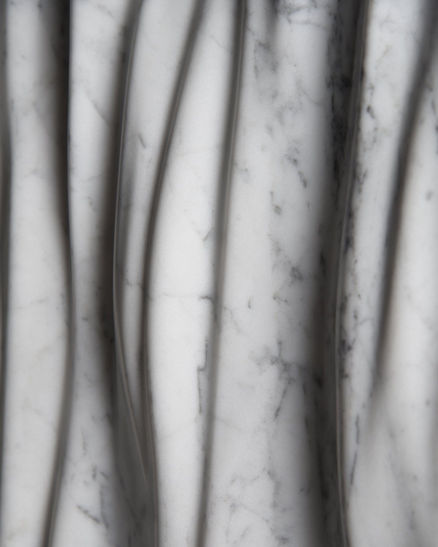 Macro detail of Carrara marble veining and smooth carved folds on the Eternal sculpture