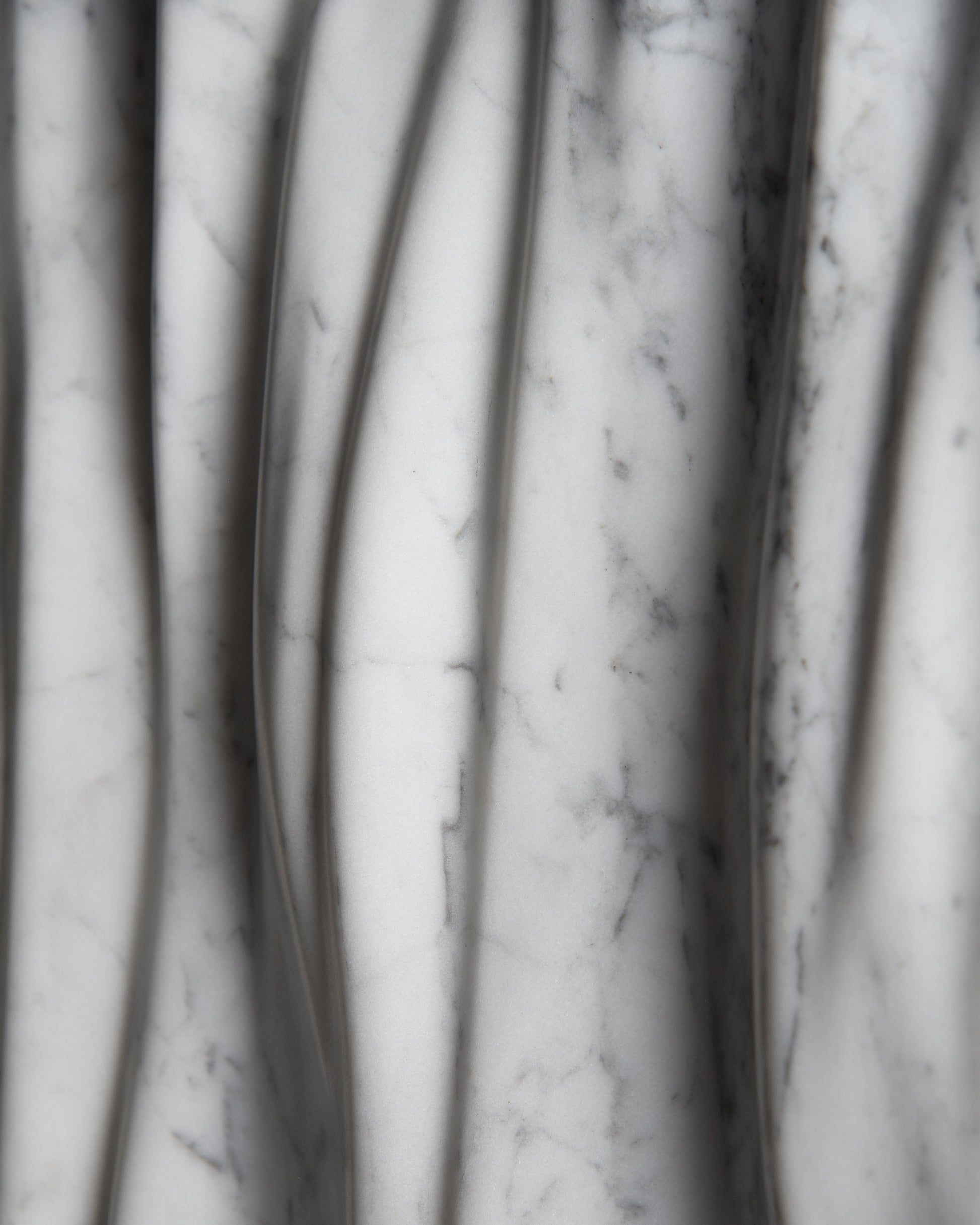 Macro detail of Carrara marble veining and smooth carved folds on the Eternal sculpture
