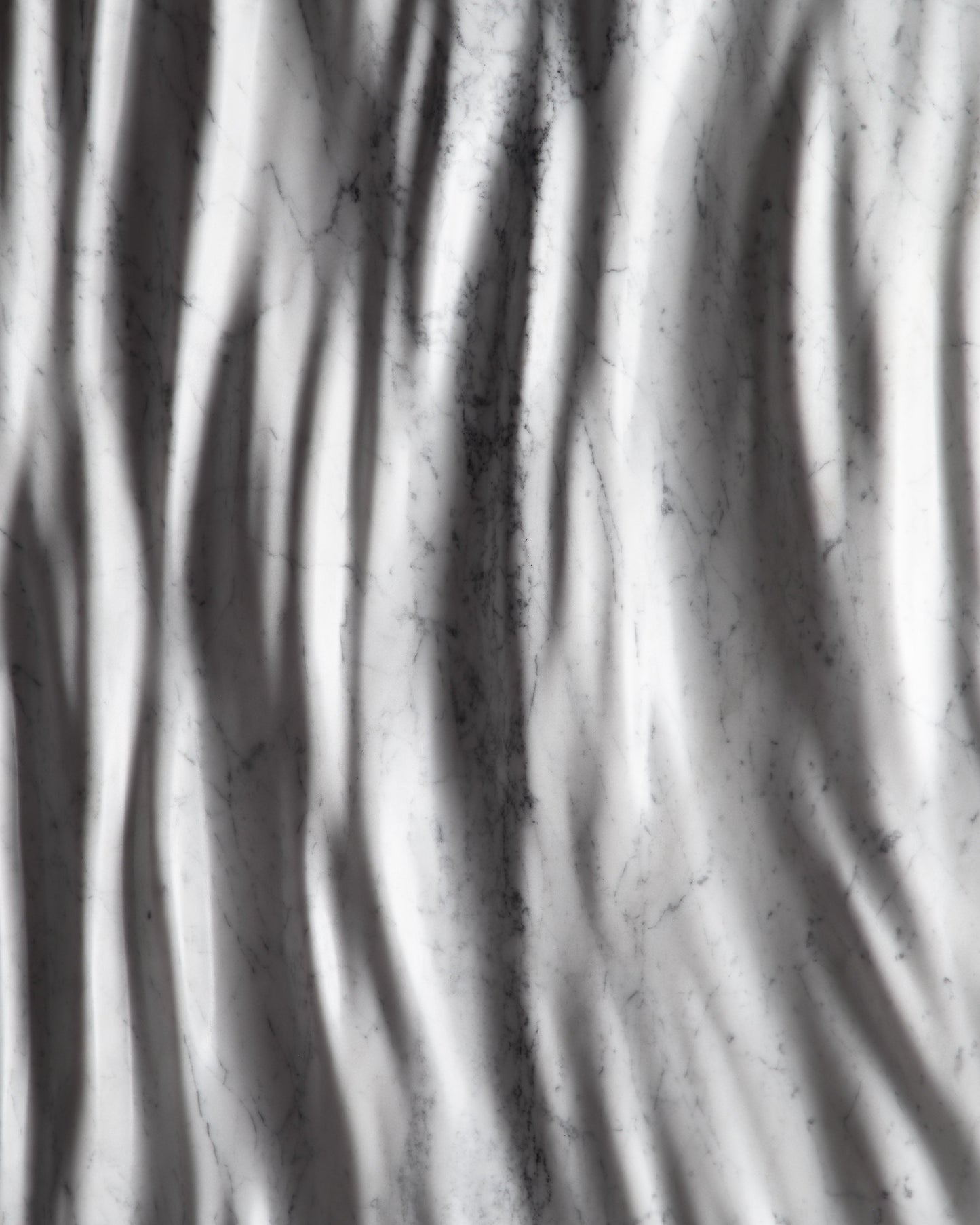 Close up of the Eternal Carrara marble sculpture showing vertical carved folds and soft shadows