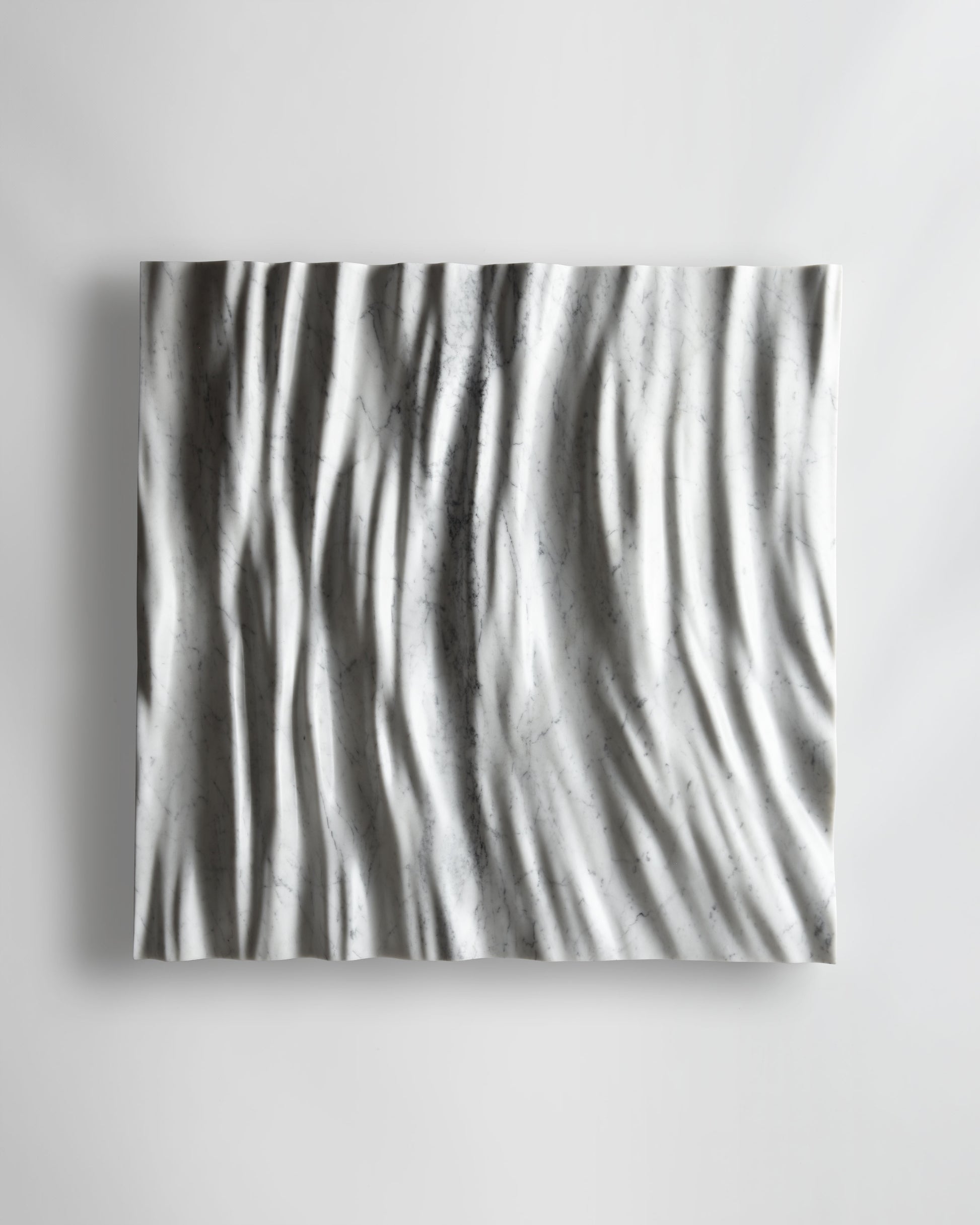 Eternal Carrara marble wall sculpture front view with flowing vertical folds and natural grey veining