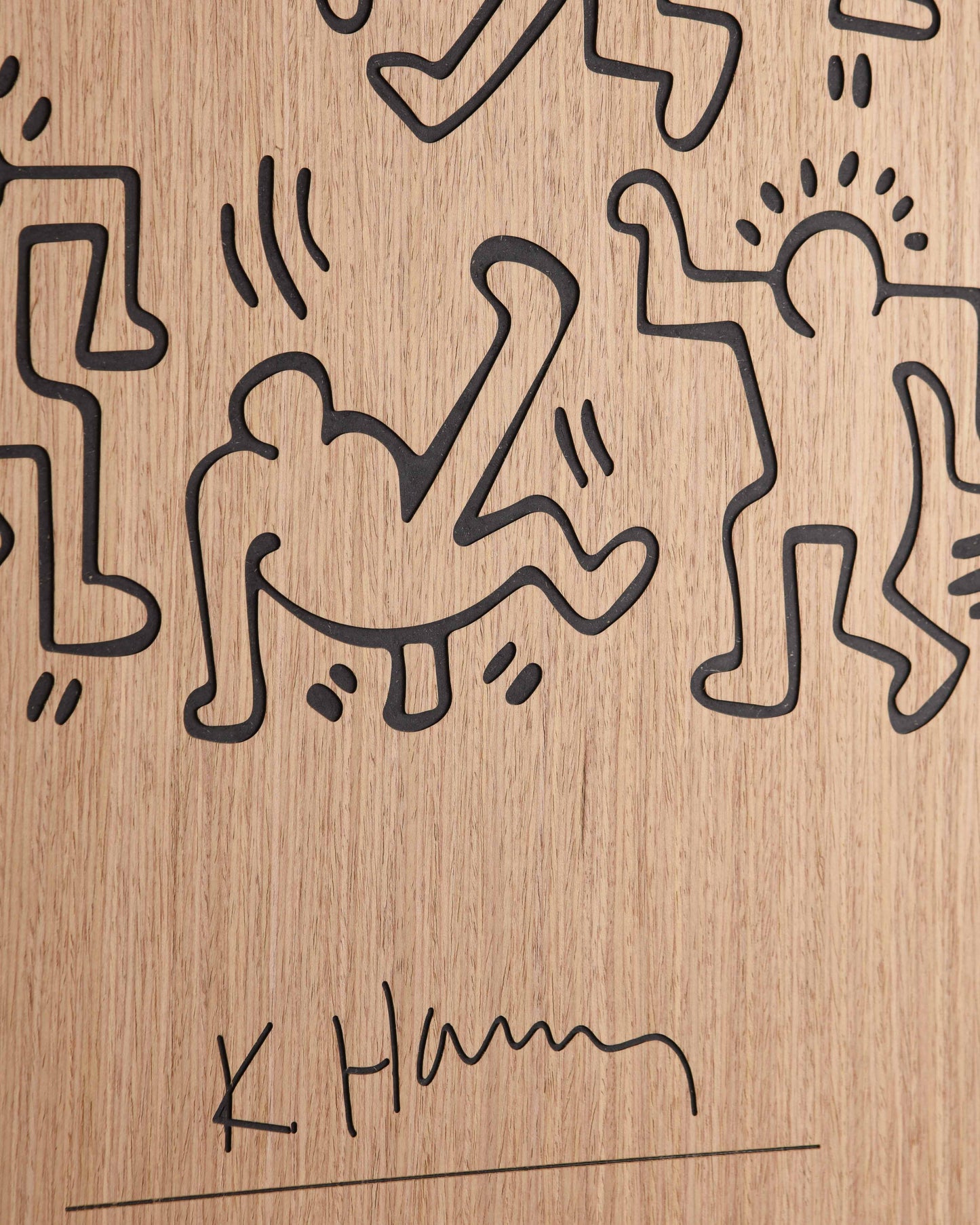 Detailed shot of the panel’s edge, showing matte black transitions against the warm oak grain and precise carving for each dancer line.