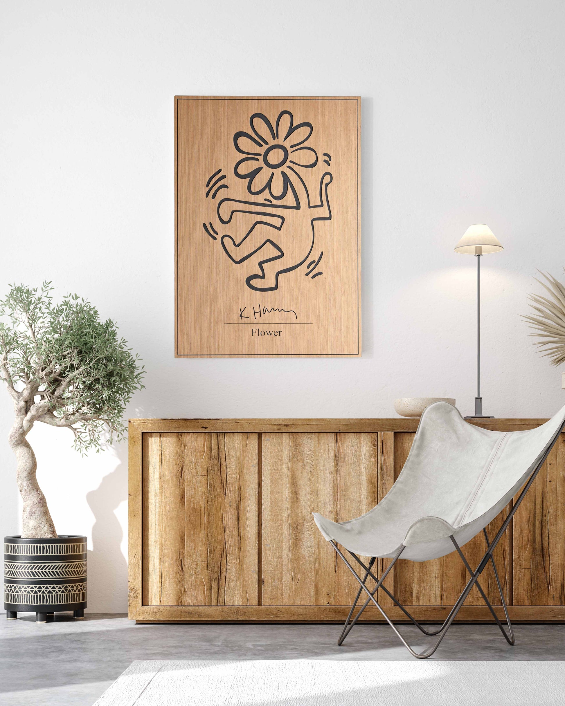 A rectangular oak-and-black wood panel featuring Kate Harring’s ‘Flower’ motif, hung above a neutral sofa for a bold focal point.