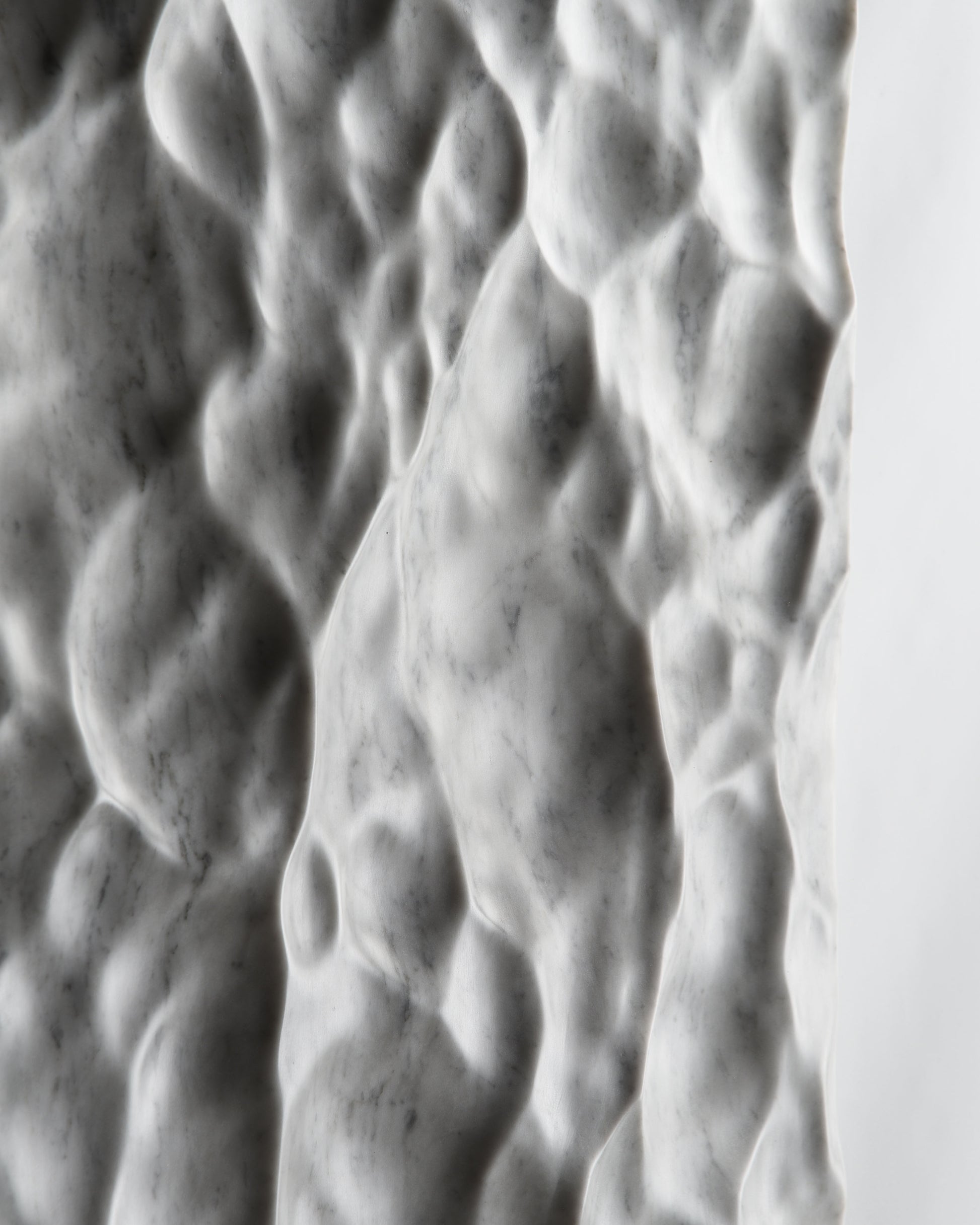 Close up of deep carved relief on Carrara marble with dramatic shadow contrast