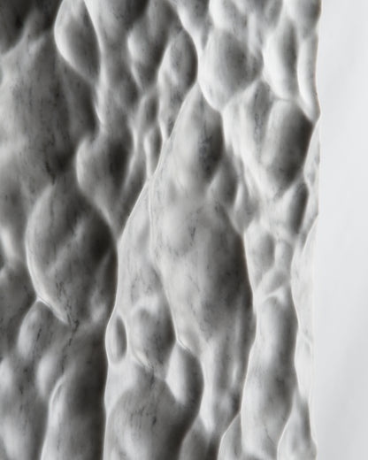Close up of deep carved relief on Carrara marble with dramatic shadow contrast