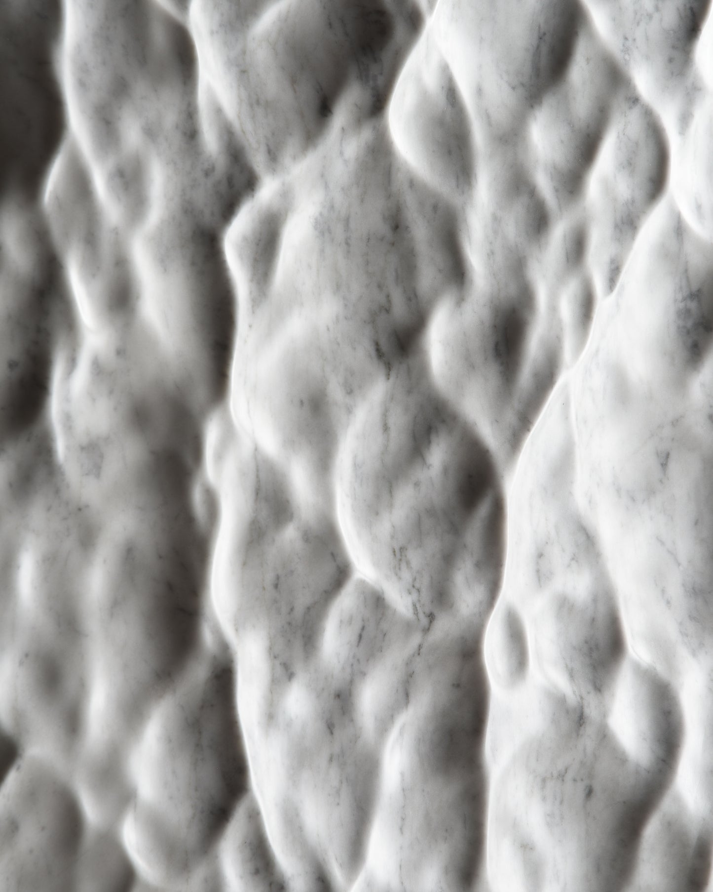 Detail of the sculpted Carrara marble surface showing a liquid like texture and natural veining