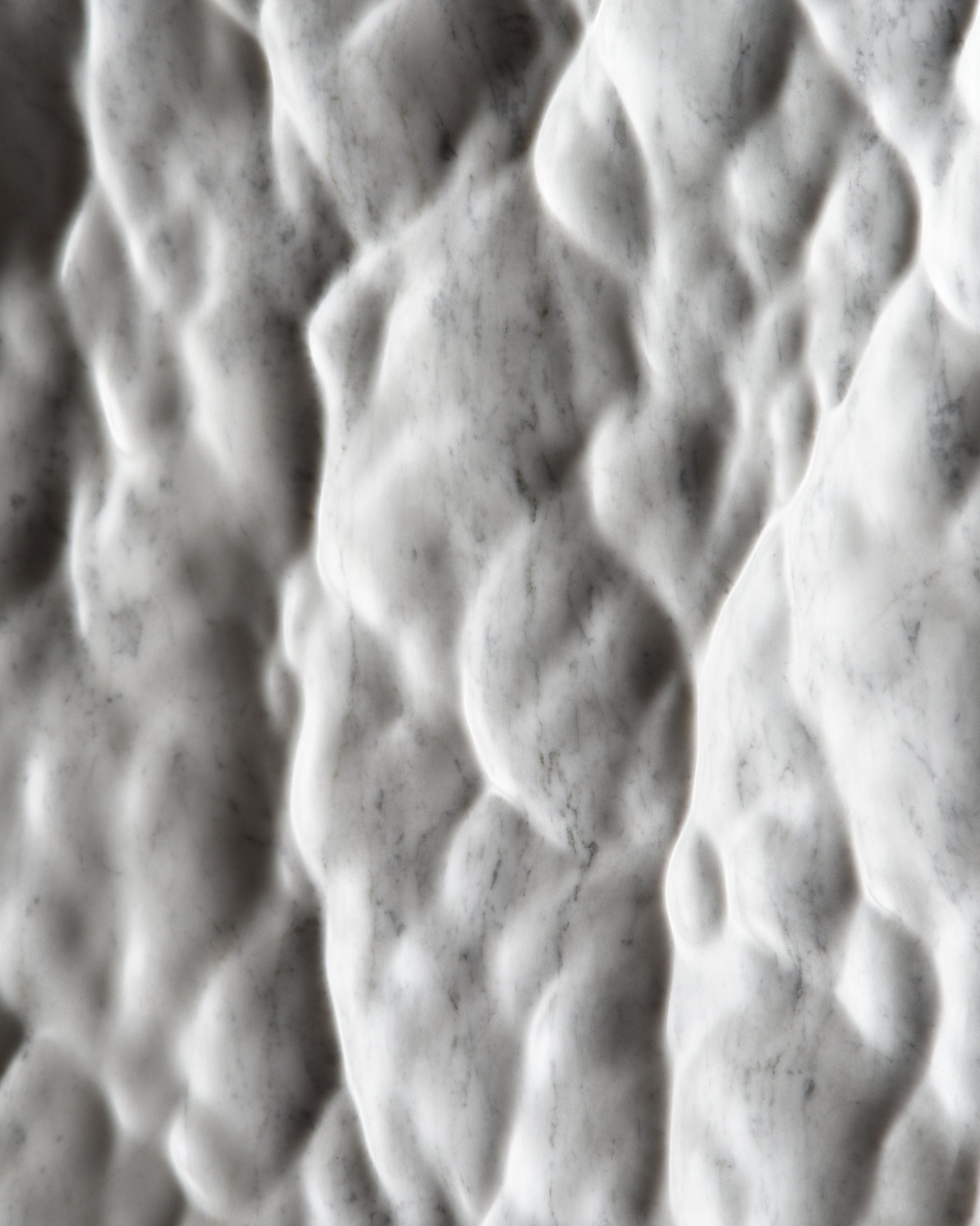 Detail of the sculpted Carrara marble surface showing a liquid like texture and natural veining