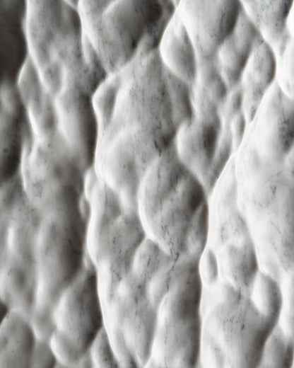 Detail of the sculpted Carrara marble surface showing a liquid like texture and natural veining