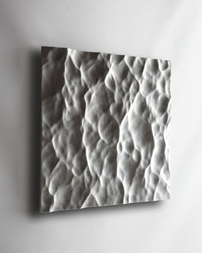 Angled view of the Liquid Marble Carrara wall sculpture installed on a white wall