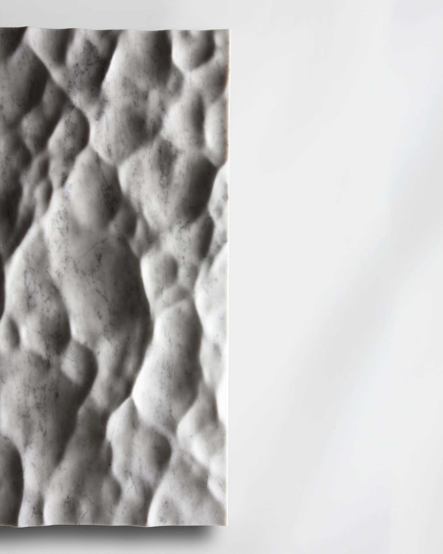 Side detail of the Liquid Marble Carrara sculpture showing edge depth and sculpted surface movement