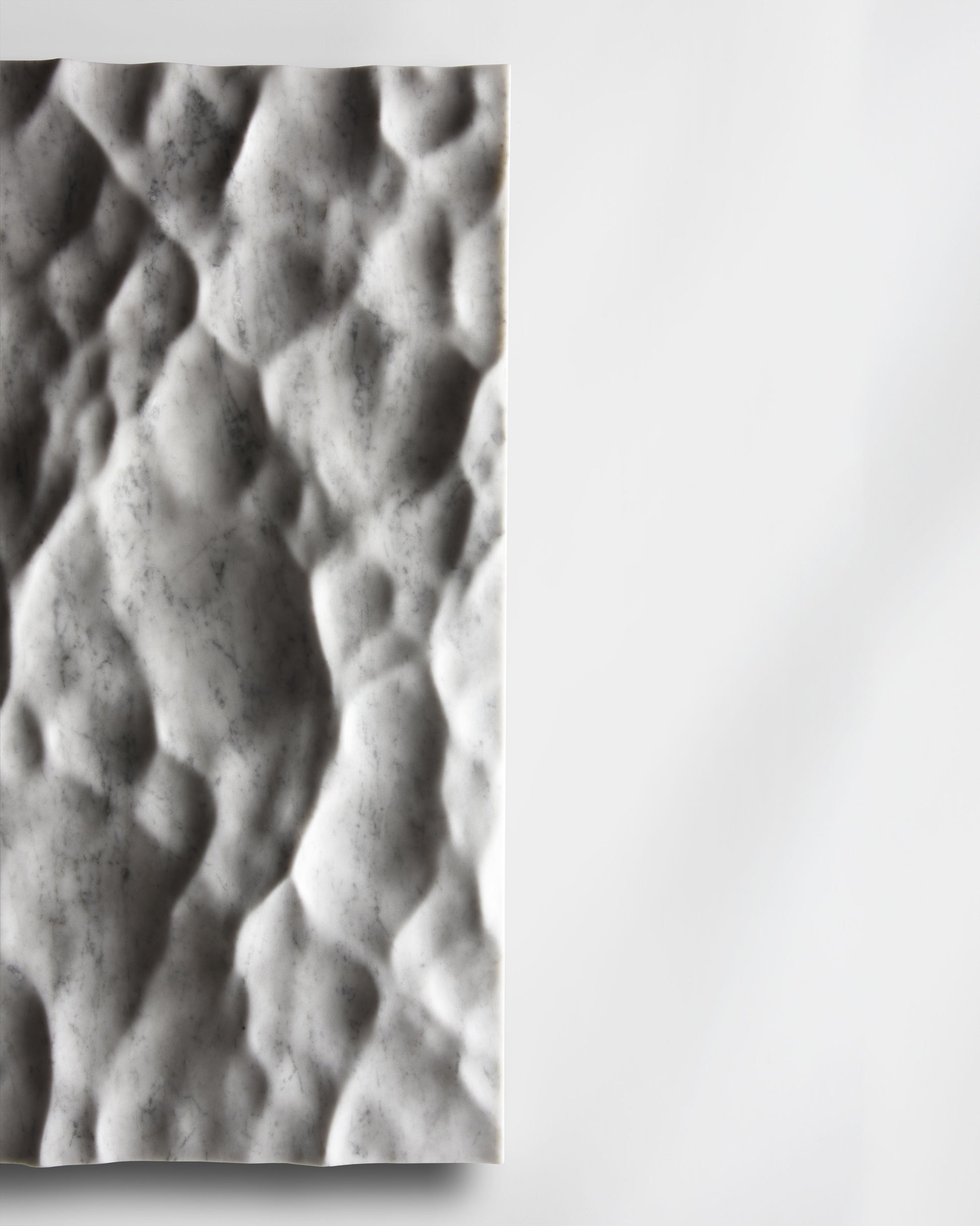 Side detail of the Liquid Marble Carrara sculpture showing edge depth and sculpted surface movement