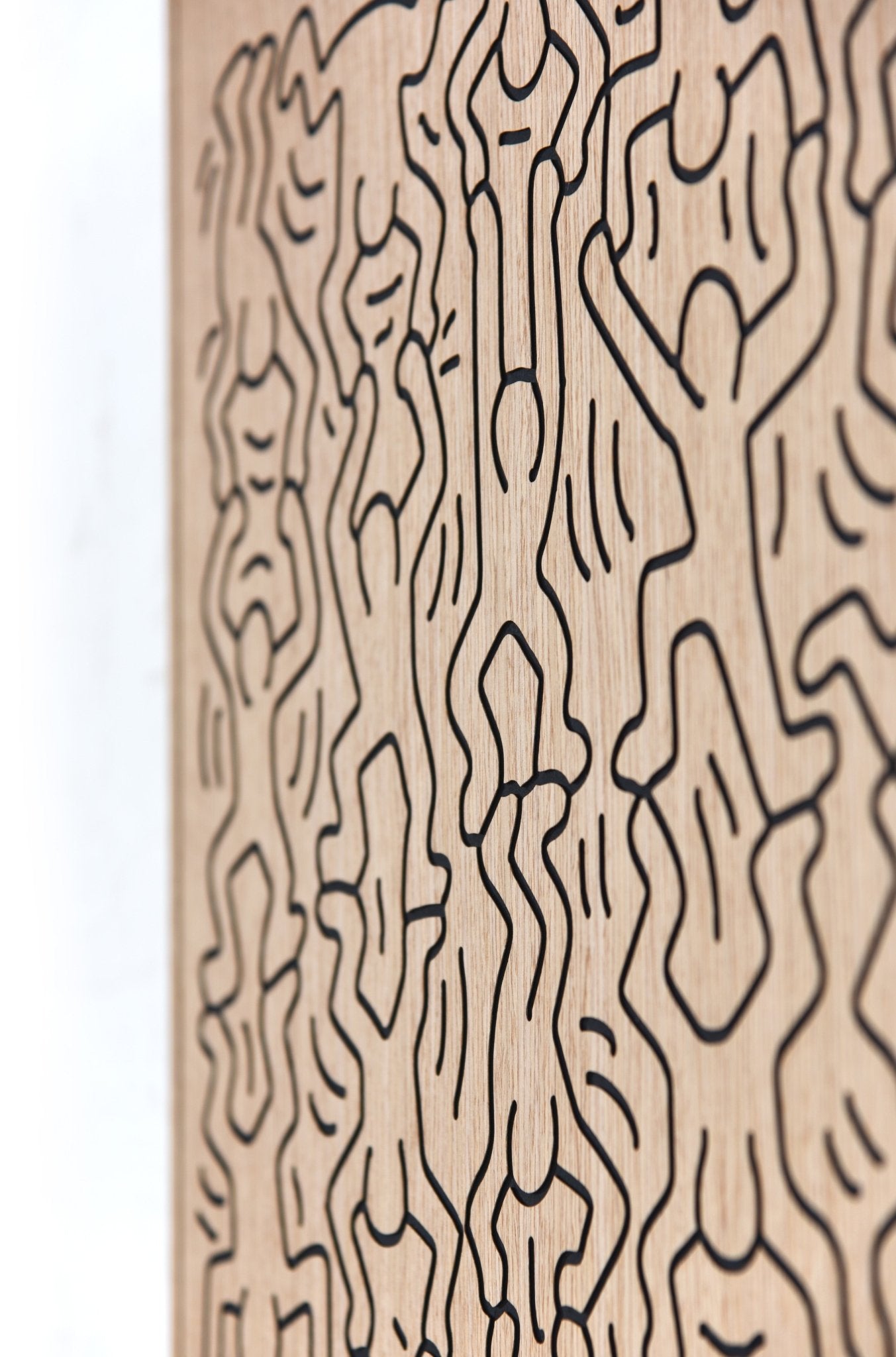 Little Men Keith Haring-inspired carved oak wall art, angled close-up of the black linework