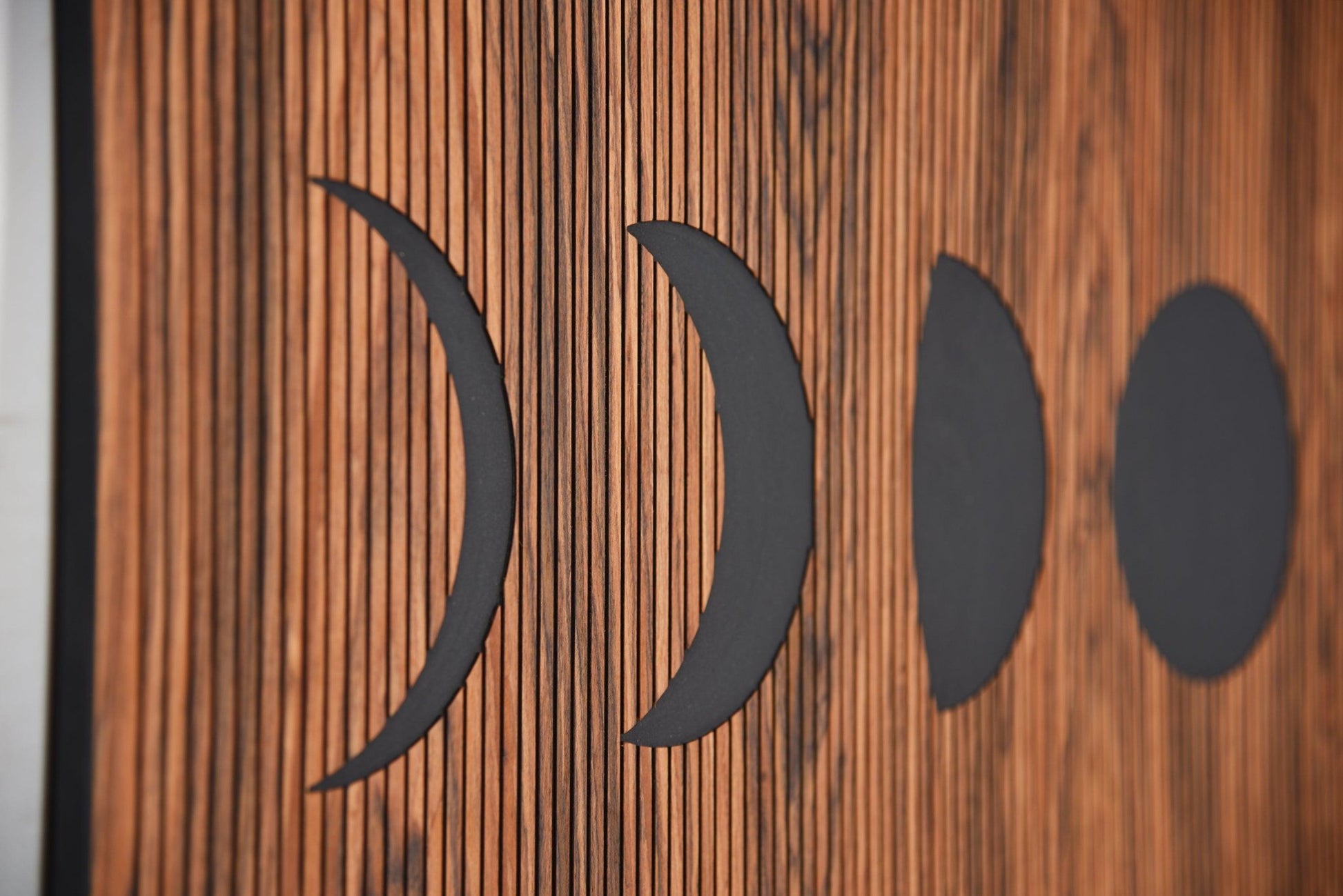 Close up of moon phases shapes on rosewood, engraved line texture detail