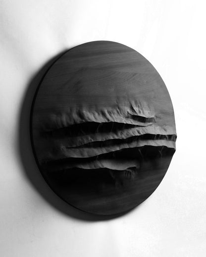 Angled front view of Mountain Echo Black, a round wood wall sculpture with layered mountain relief
