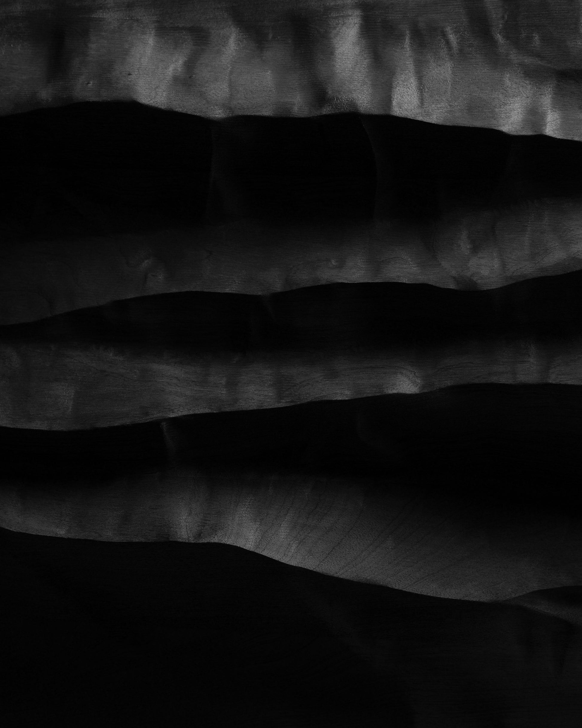 Macro detail of layered black wood ridges and deep shadows across the Mountain Echo wall sculpture