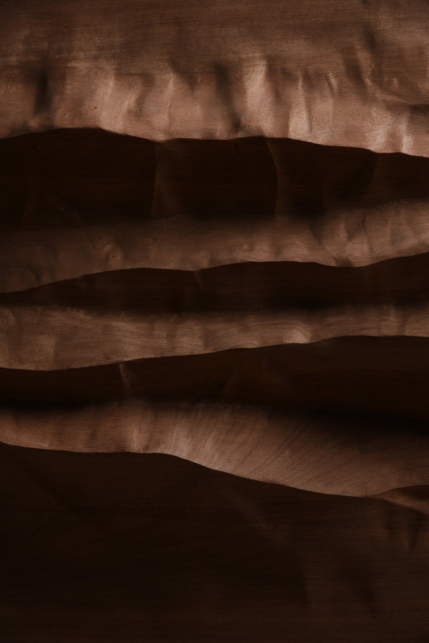 Macro detail of deep relief and shifting shadows across the mahogany surface of Mountain Echo