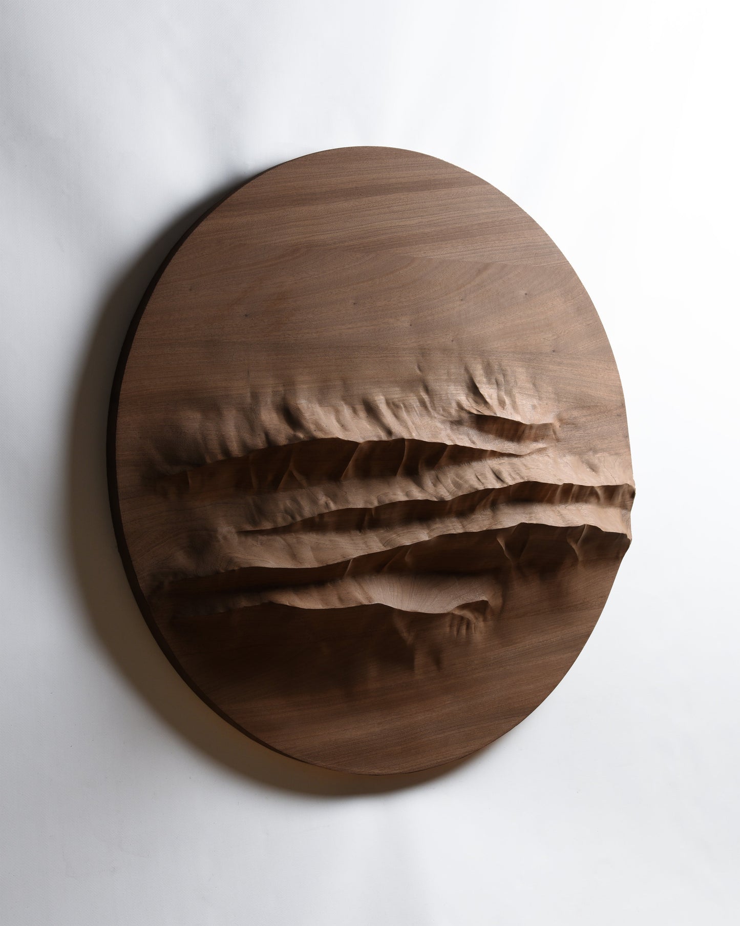 Angled front view of Mountain Echo, a round mahogany wall sculpture inspired by the Dolomites