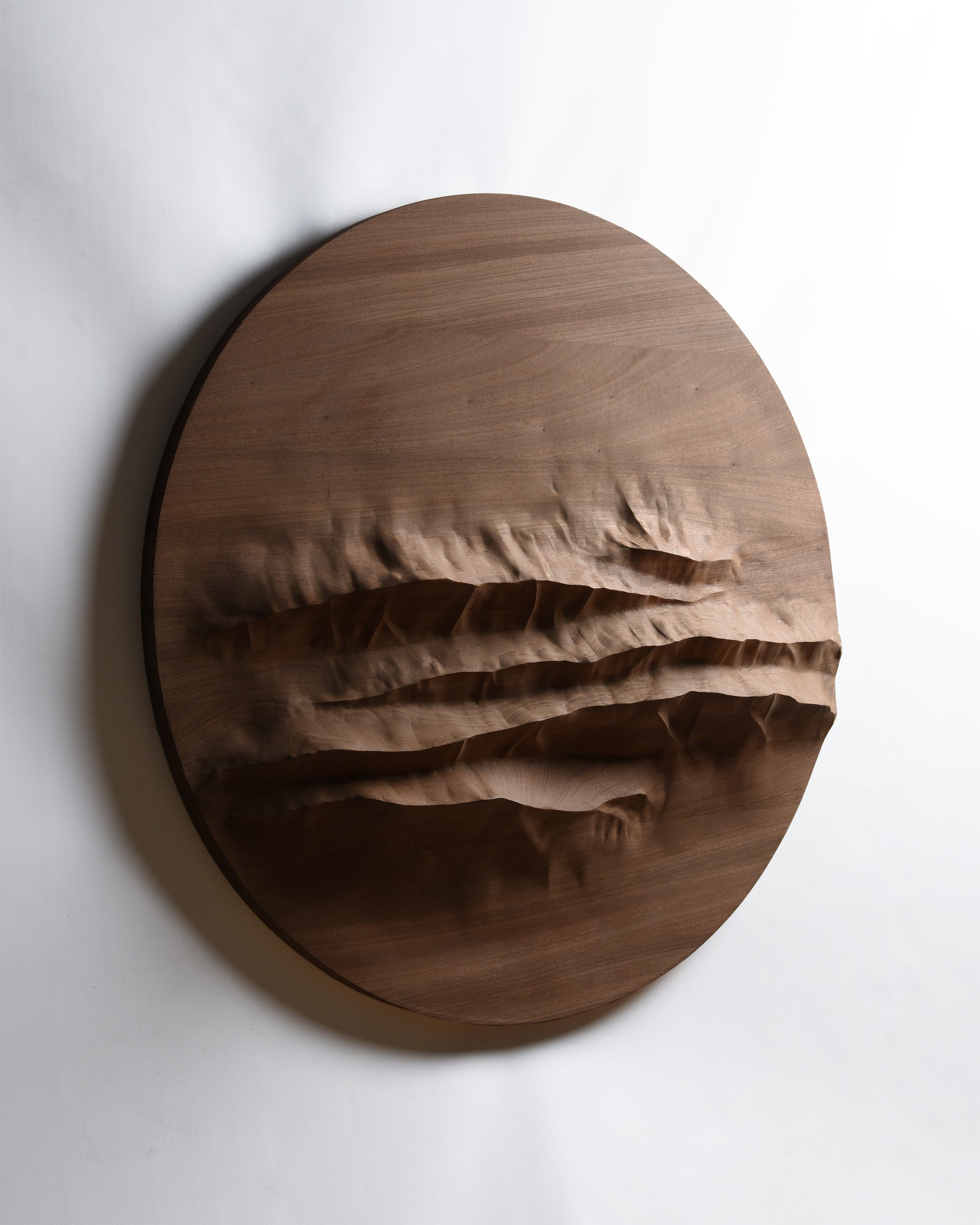 Angled front view of Mountain Echo, a round mahogany wall sculpture inspired by the Dolomites