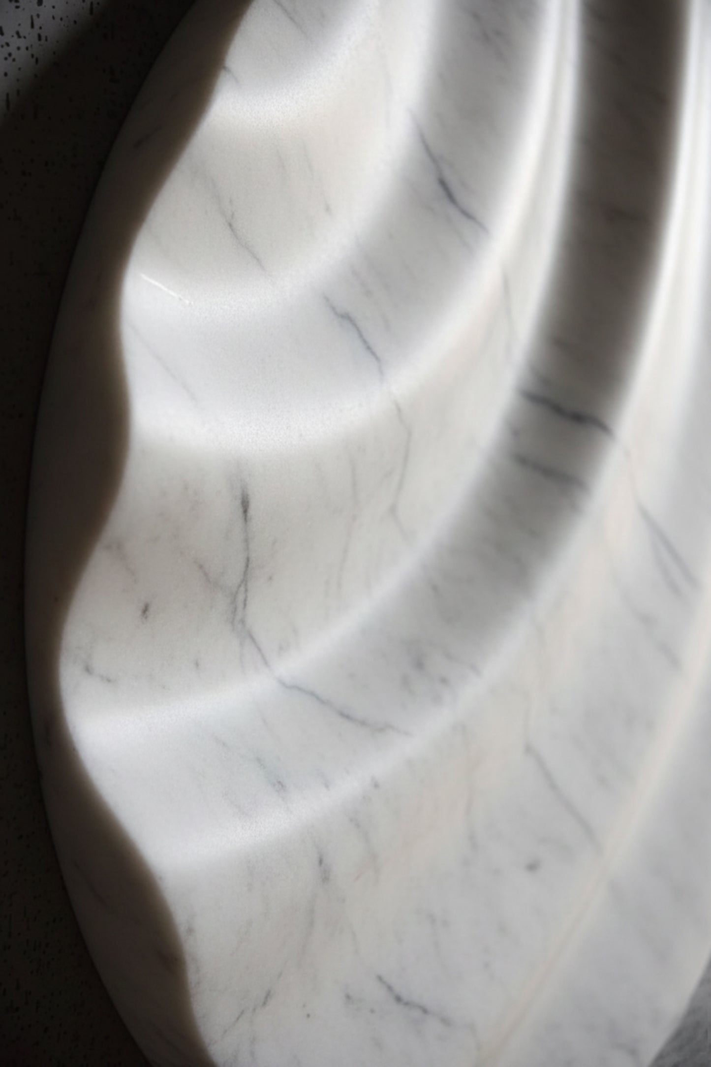 Close-up of white marble wall sculpture showing smooth grooves and natural veining