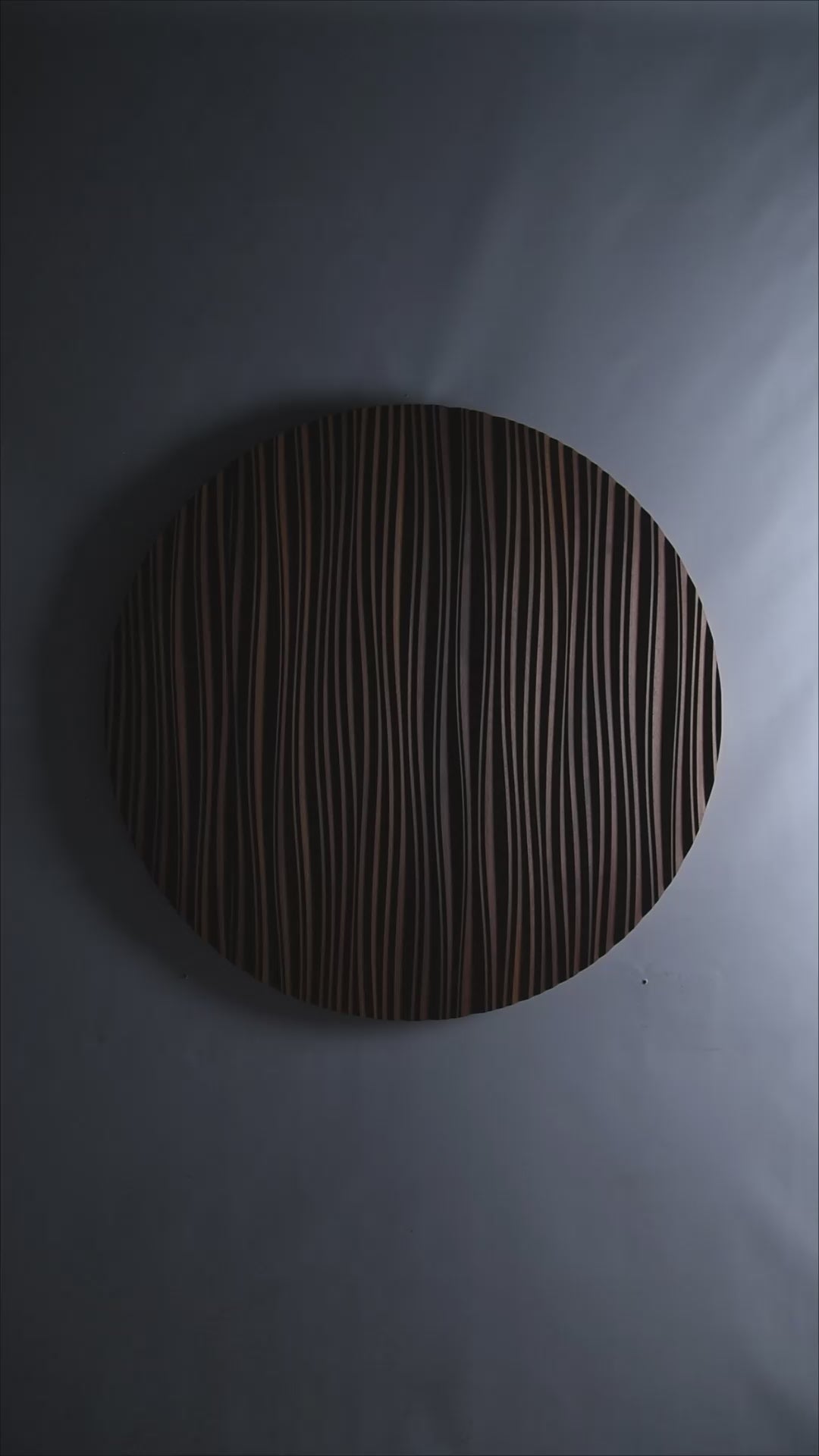 A circular Iroko ‘The Line’ panel mounted above a sofa, blending big wall decor appeal with scandi interior elegance in a softly lit space