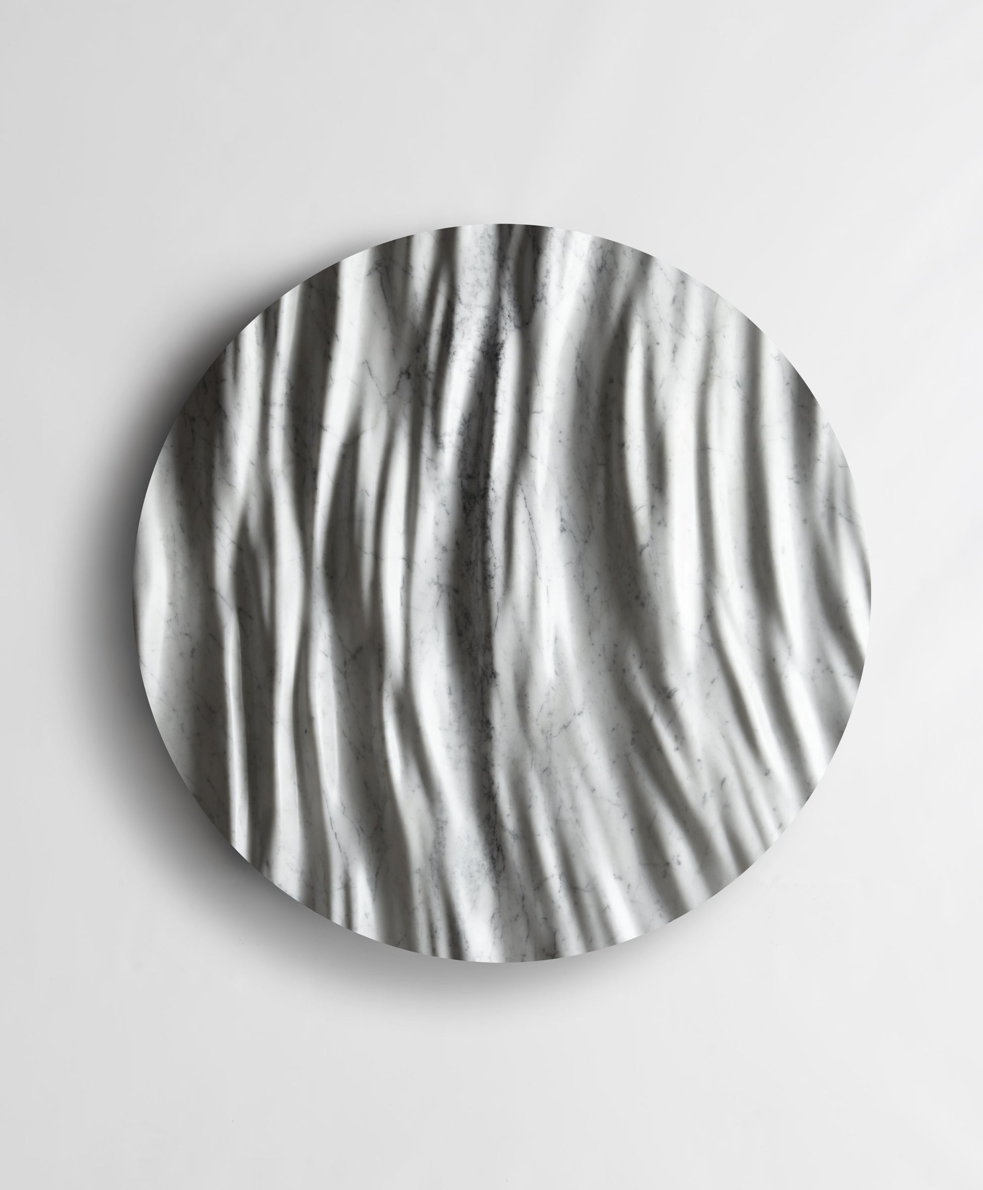 Round Eternal Carrara marble wall sculpture front view with flowing vertical folds and natural grey veining