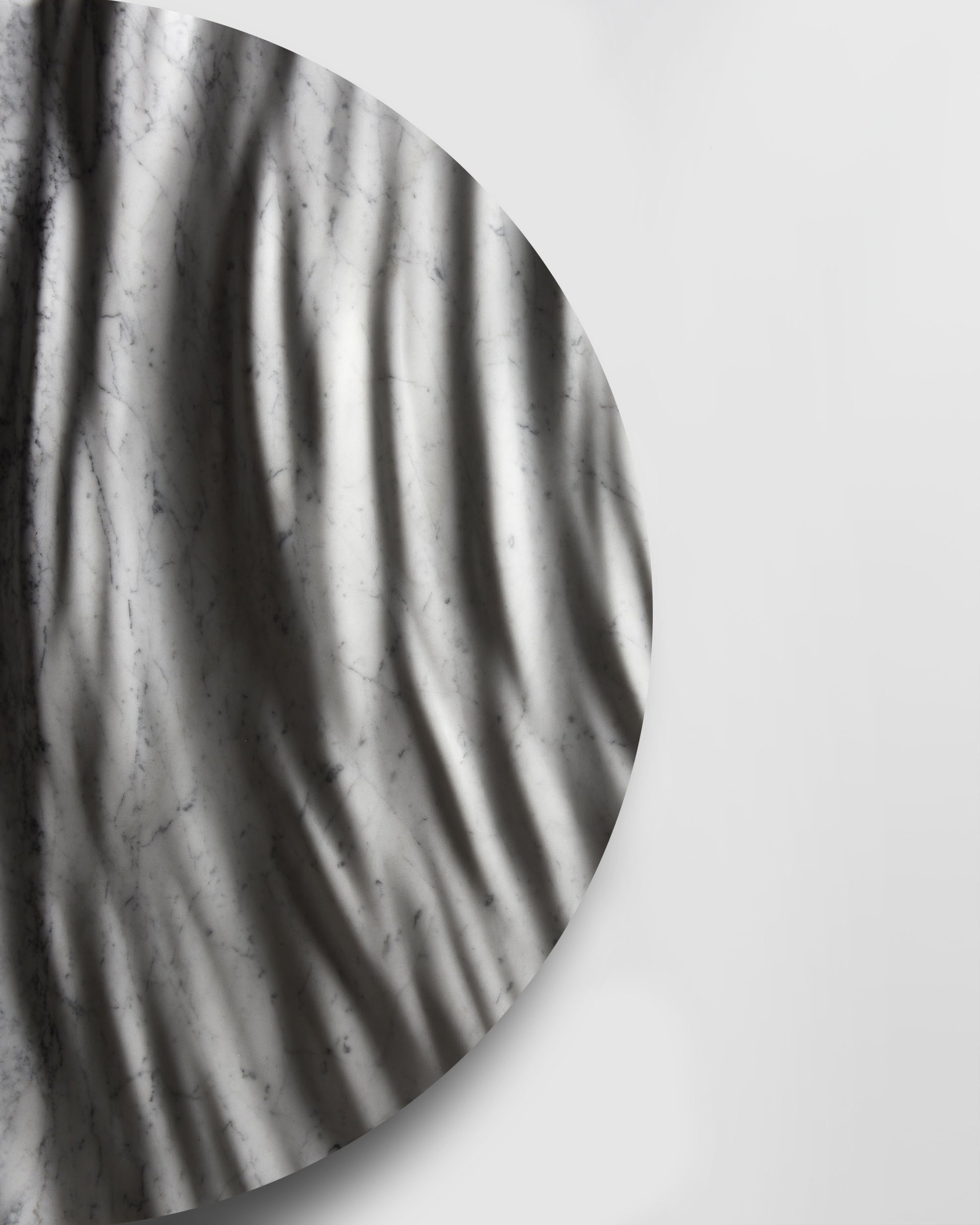 Side detail of the Round Eternal Carrara marble sculpture showing carved depth, edge thickness, and soft shadows