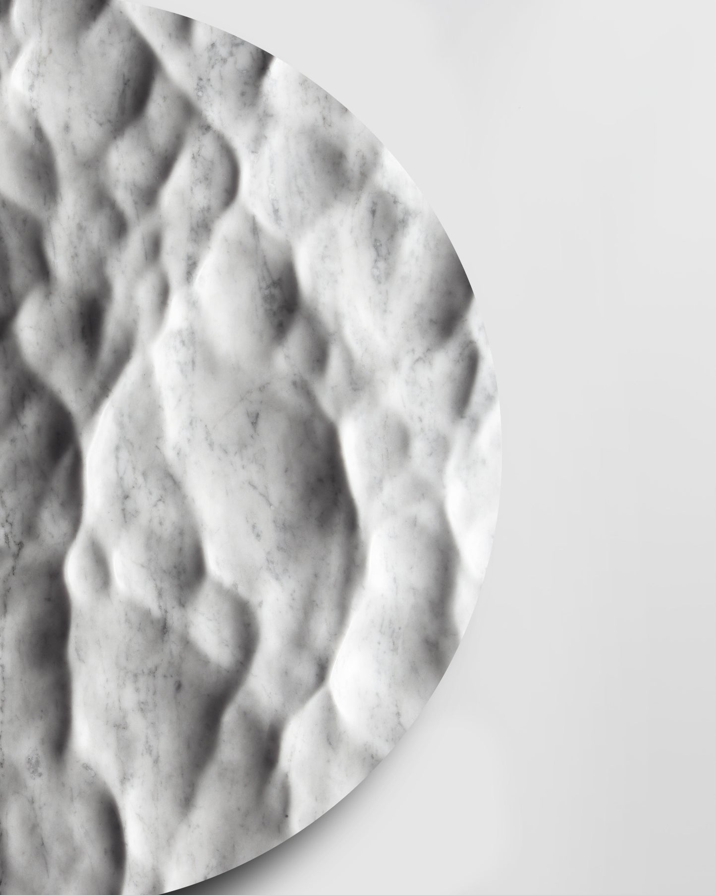 Side detail of the Round Liquid Marble Carrara sculpture showing carved depth, edge thickness, and soft shadows