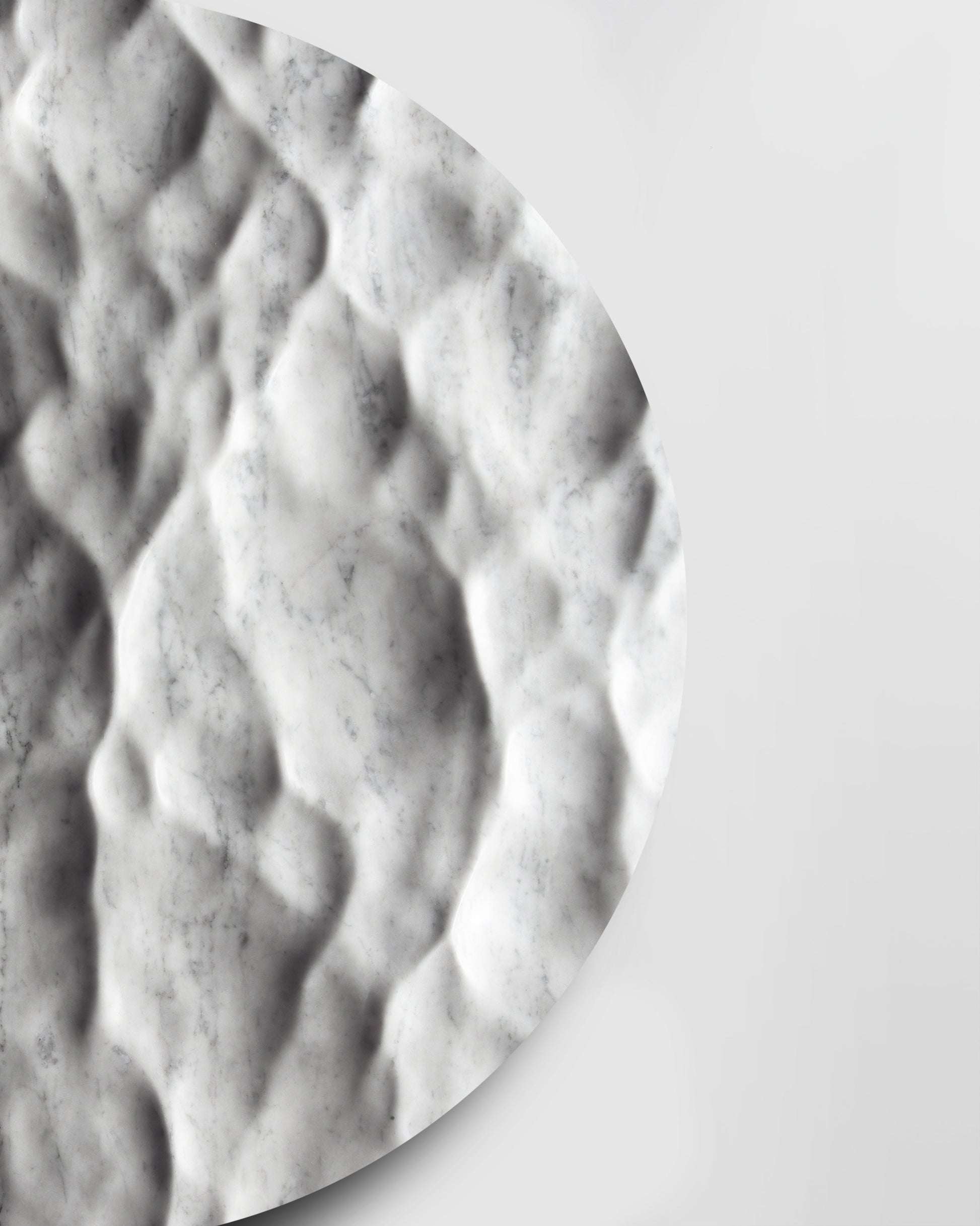 Side detail of the Round Liquid Marble Carrara sculpture showing carved depth, edge thickness, and soft shadows