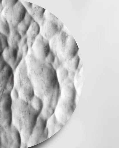 Side detail of the Round Liquid Marble Carrara sculpture showing carved depth, edge thickness, and soft shadows