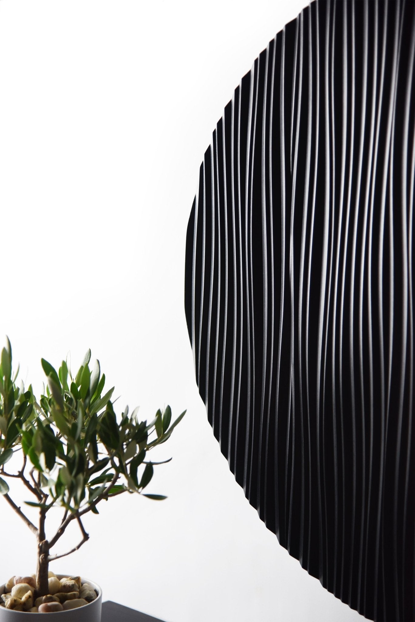 Edge close up of the round black wall sculpture showing relief depth and shadow