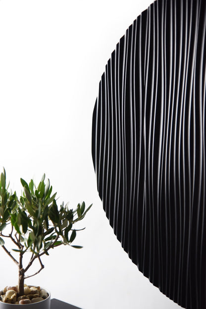 Edge close up of the round black wall sculpture showing relief depth and shadow