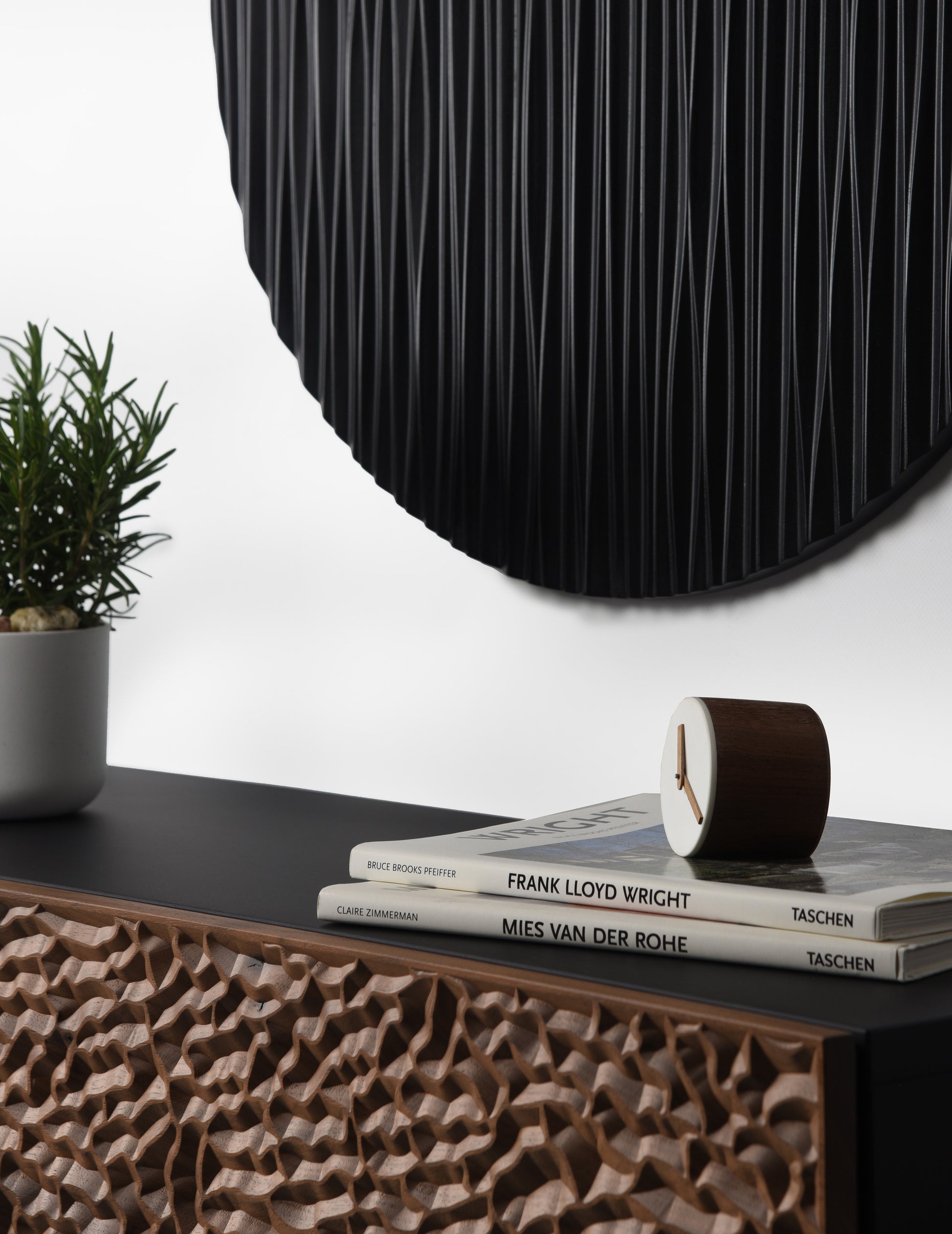 Round black wall sculpture styled above the console in a minimal interior