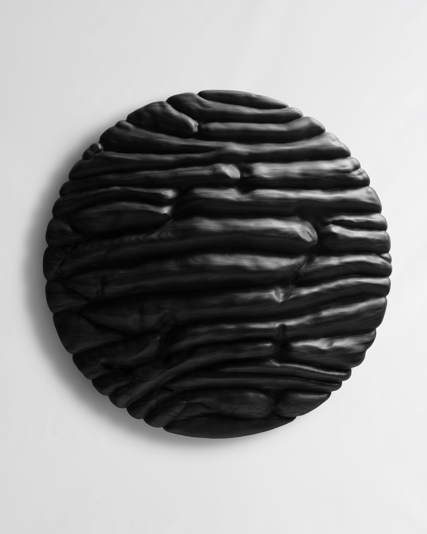 Front view of Strata Black, a round wood wall sculpture with deep layered organic relief