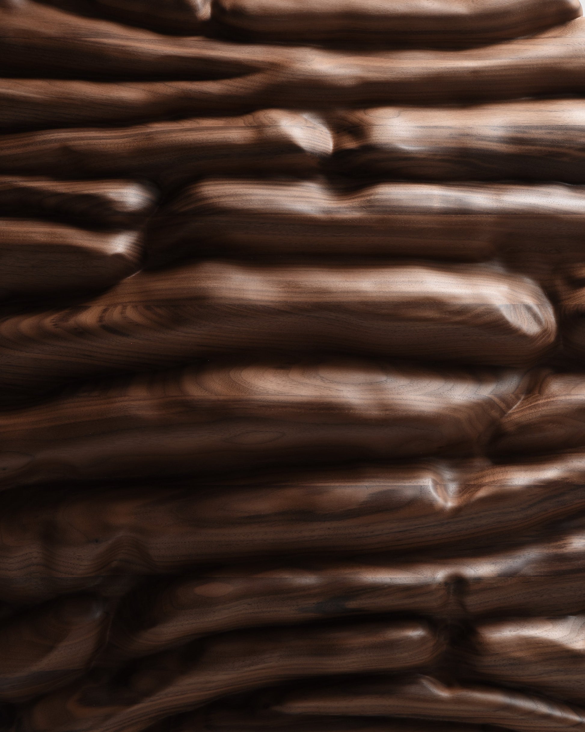 Close view of the central walnut relief showing layered forms, natural grain and softly finished surfaces