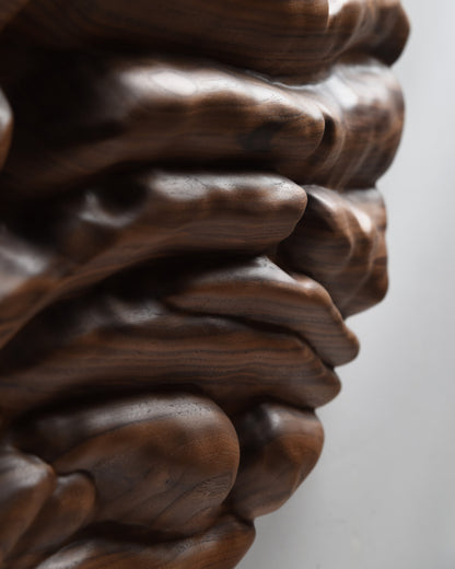 Close view of irregular layered forms along the edge of the circular walnut sculpture