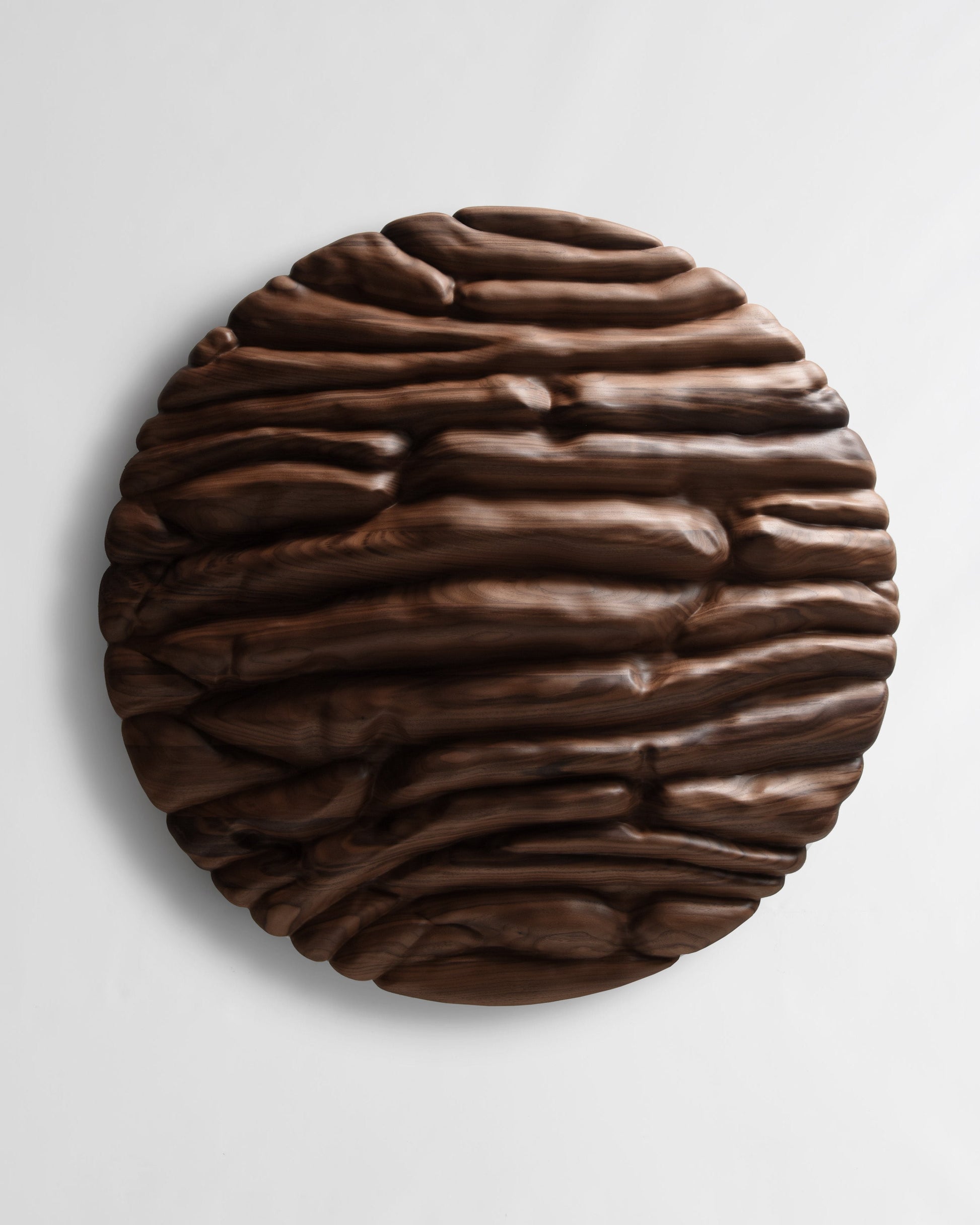 Front view of Strata, a circular Canaletto walnut wall sculpture with deep horizontal organic relief