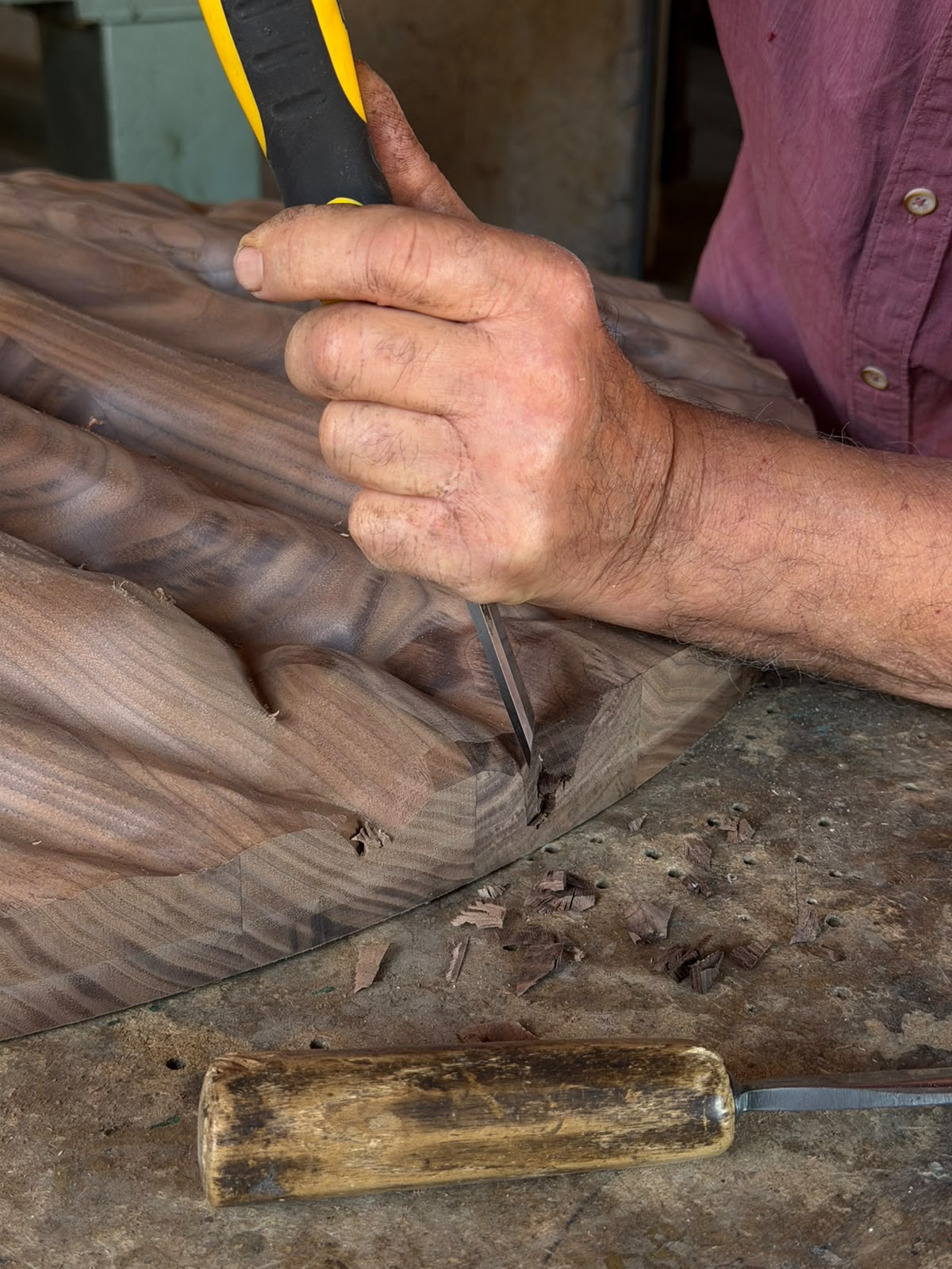 Artisan refining the walnut relief of Strata by hand with a chisel in the squareoff workshop