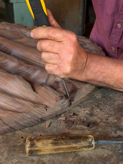 Artisan refining the walnut relief of Strata by hand with a chisel in the squareoff workshop