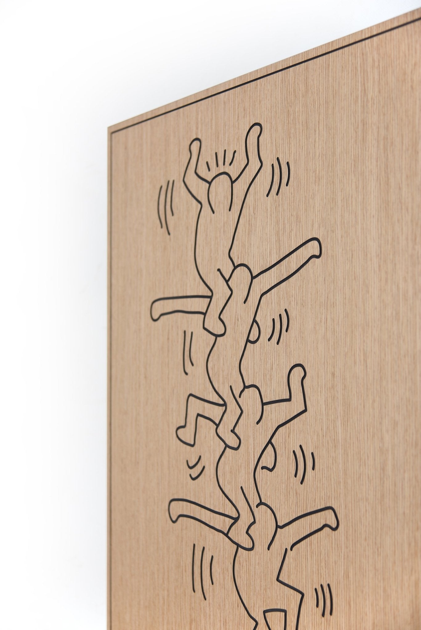 Angled close up of the carved line work on the Stunts Keith Haring oak and black wood wall panel
