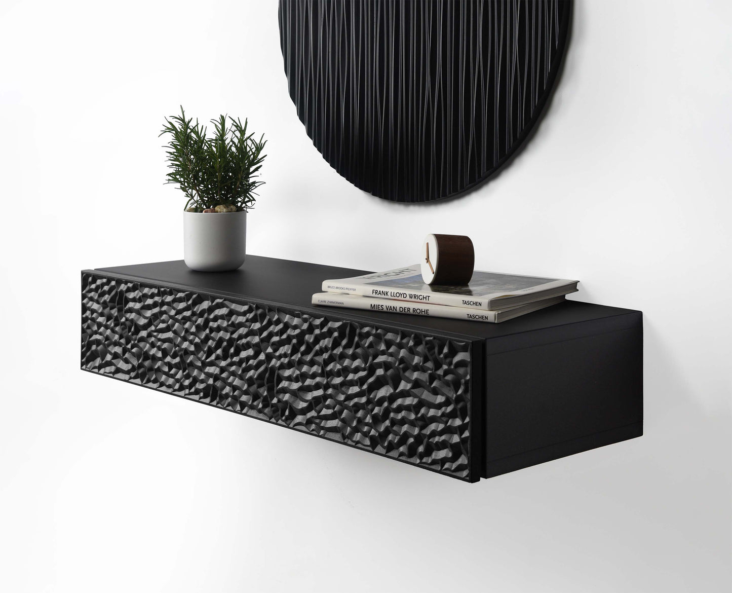 Suspended floating console in total black with carved front, styled with a round black wall sculpture above