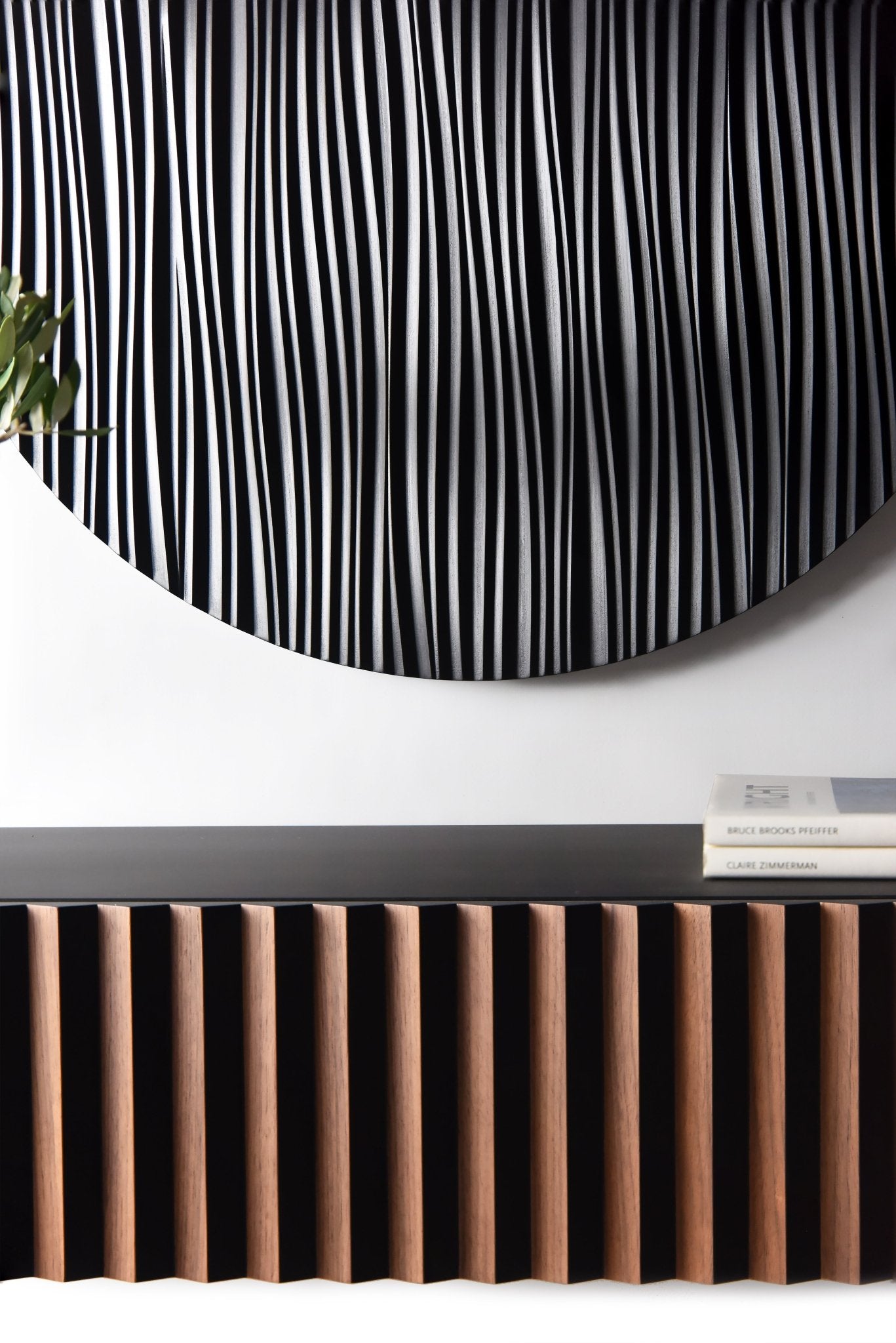 Close up of the round black wall sculpture relief above the walnut and black console